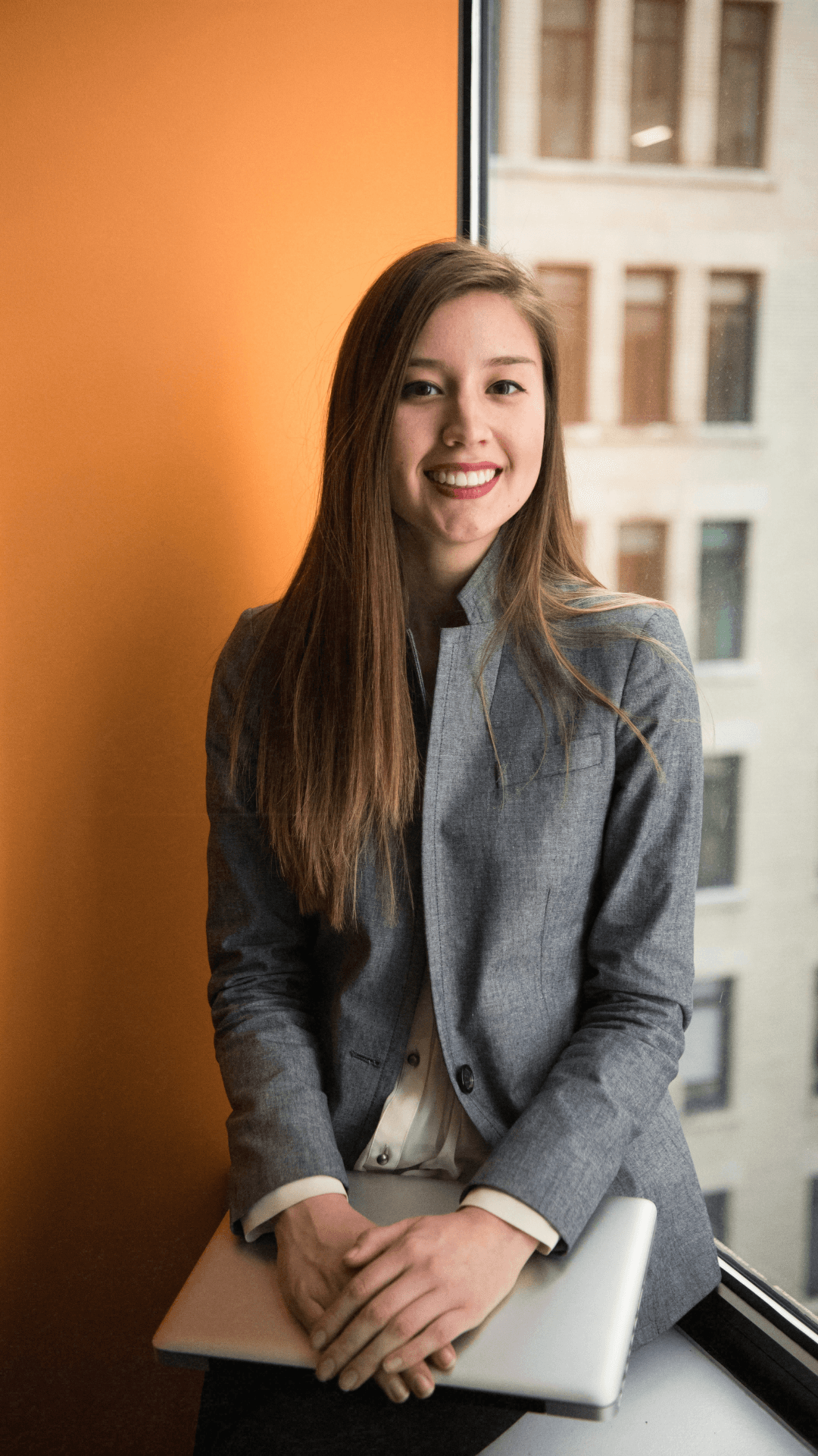 Professional woman seated by window in warm office light.