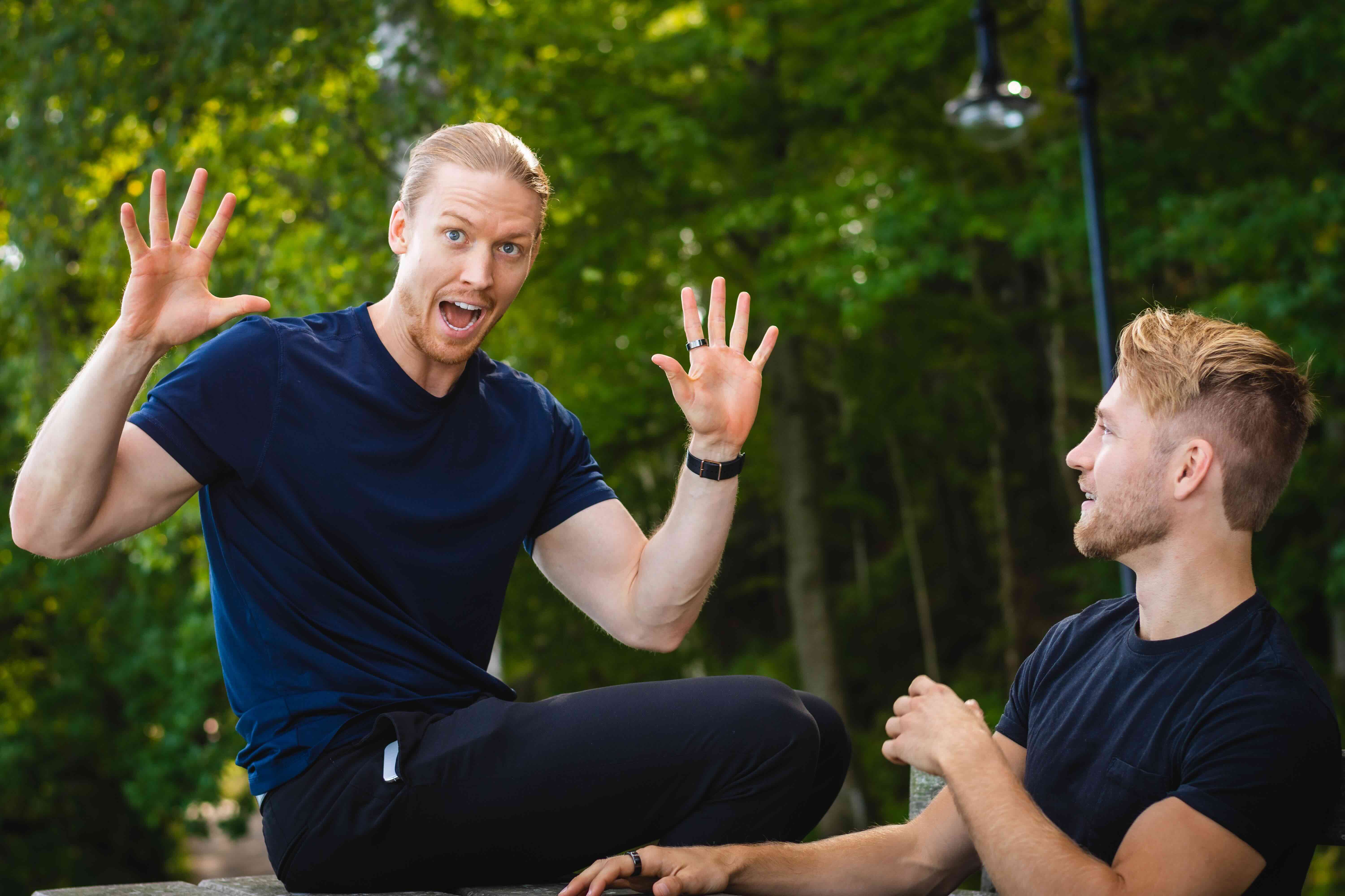 A peloton of professional cyclists in helmets and team jerseys race tightly together on a city street.