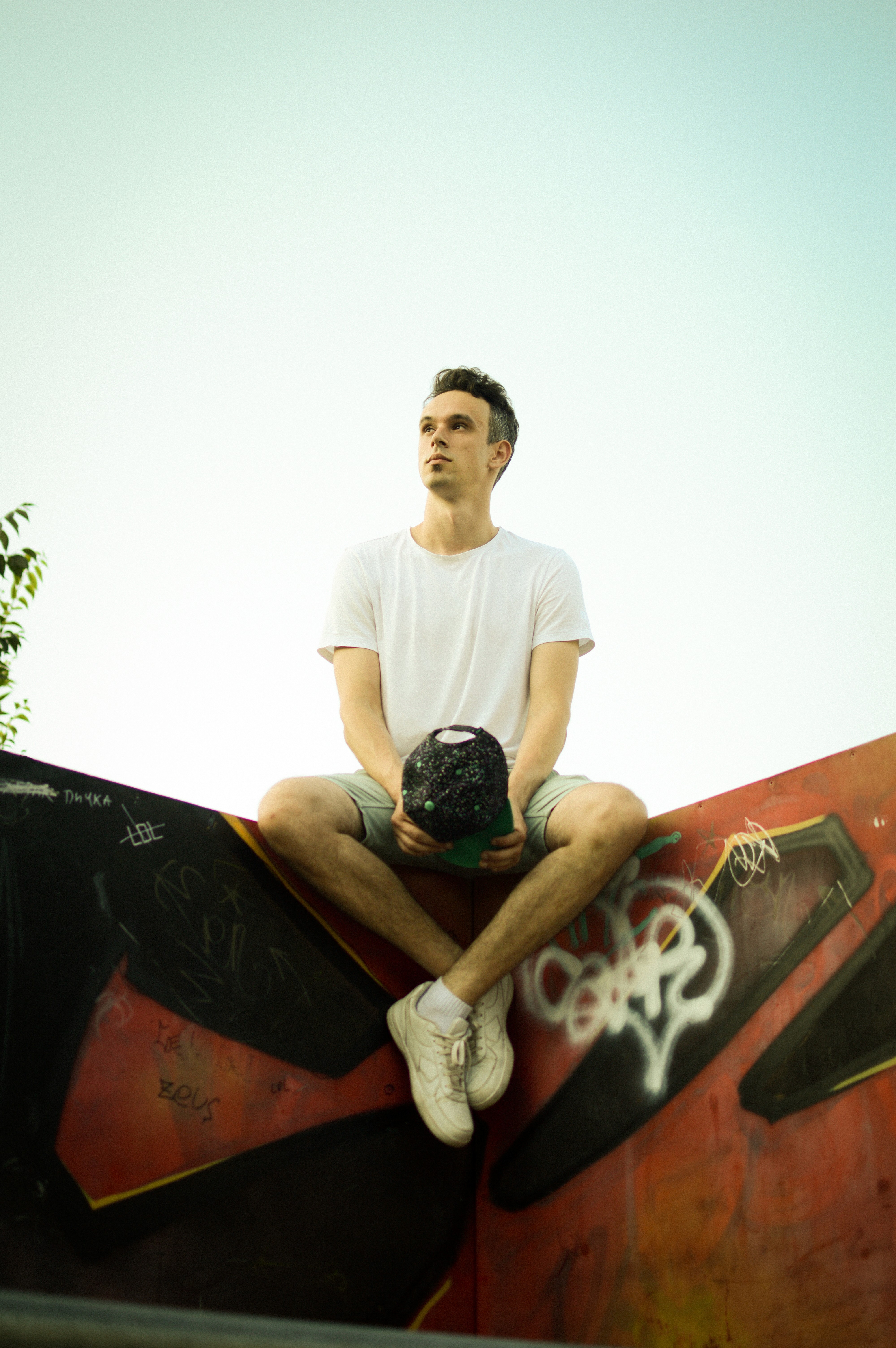 Photo showing A person relaxes on a skate ramp wearing protective gear outdoors.