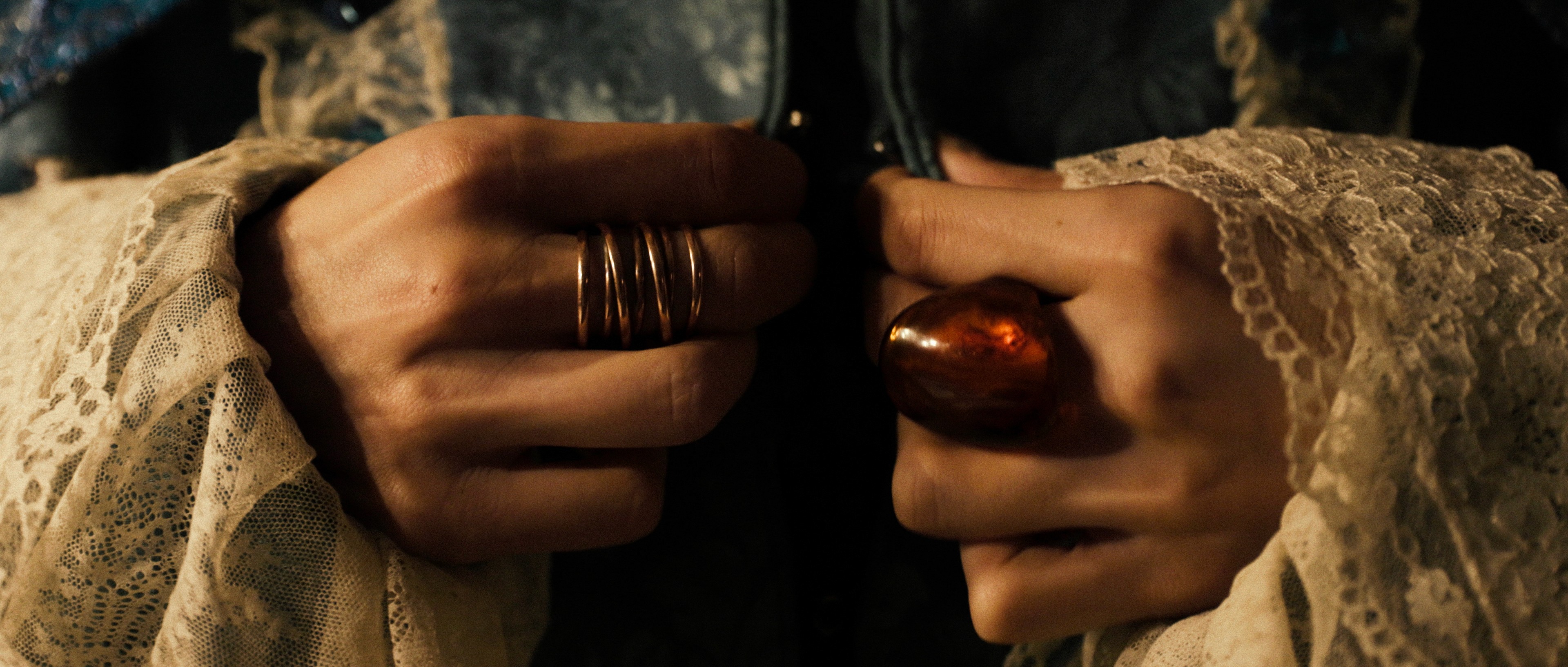 Detail shot of hands wearing rings, warm cinematic color grading.