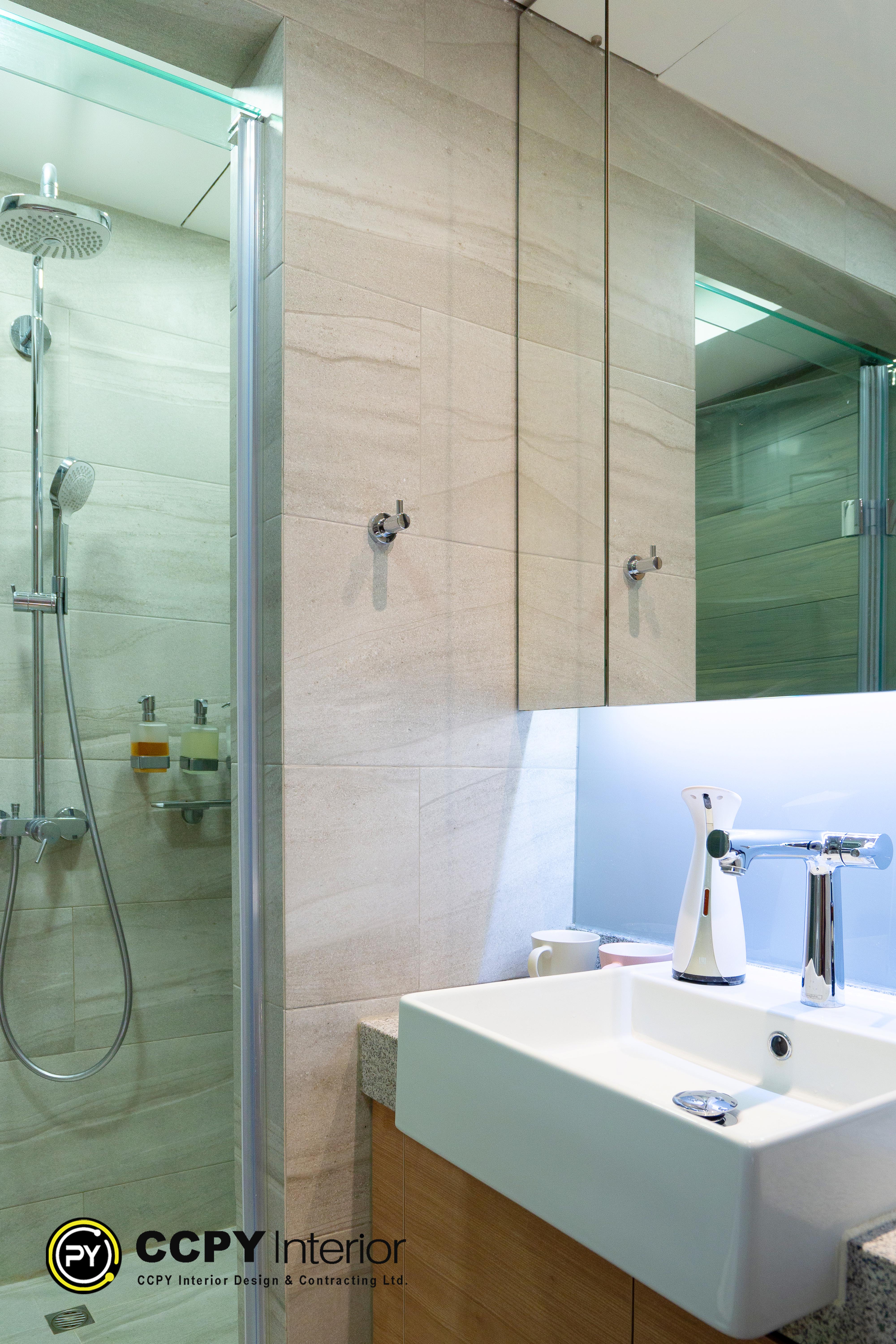 Key Design FeaturesMirrored Cabinetry: Large, clean-edged mirrors double as storage and reflect light to make the compact space look bigger.Under-Cabinet Lighting: A soft blue LED strip is installed beneath the mirror, providing functional illumination and a modern, sensory vibe.Minimalist Shower Fixtures: Features a sleek chrome handheld shower head set against neutral-toned, subtly textured square tiles.Glass Enclosure: A frameless glass partition separates the wet area without visually cutting off the limited floor space.