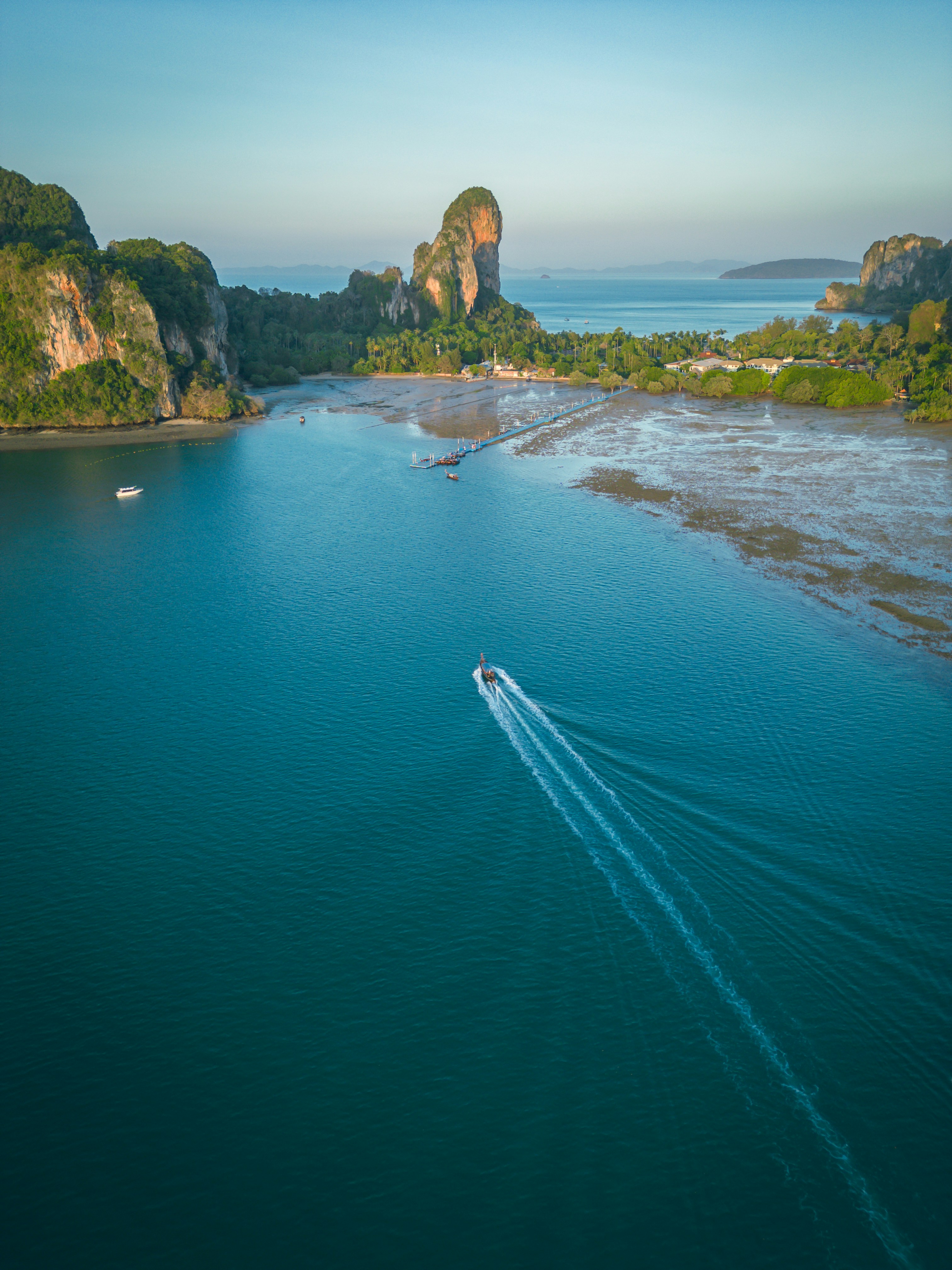 Boat speeds through turquoise water near limestone cliffs.