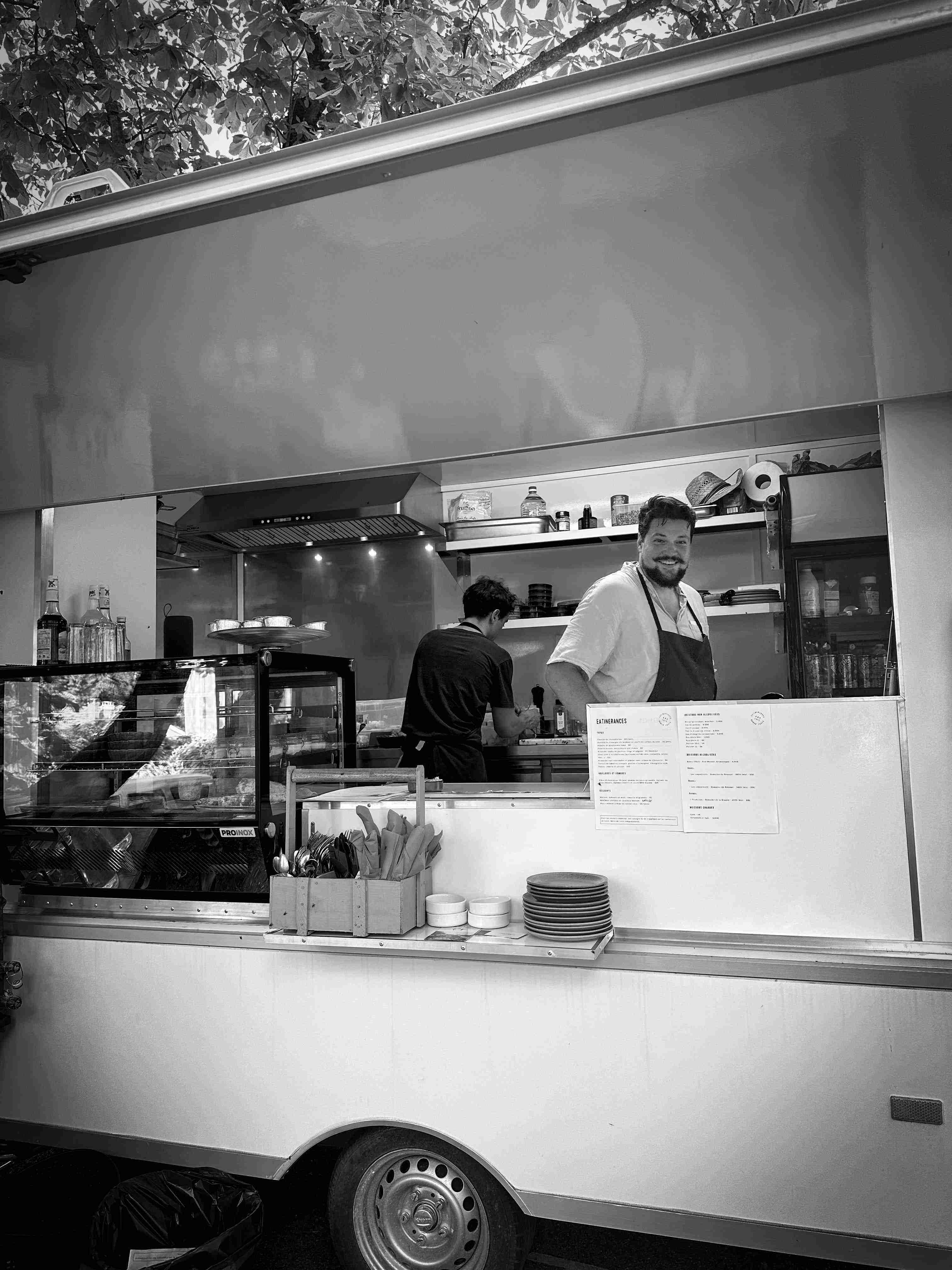 Chef traiteur en cuisine mobile préparant des plats frais pour événement en extérieur.