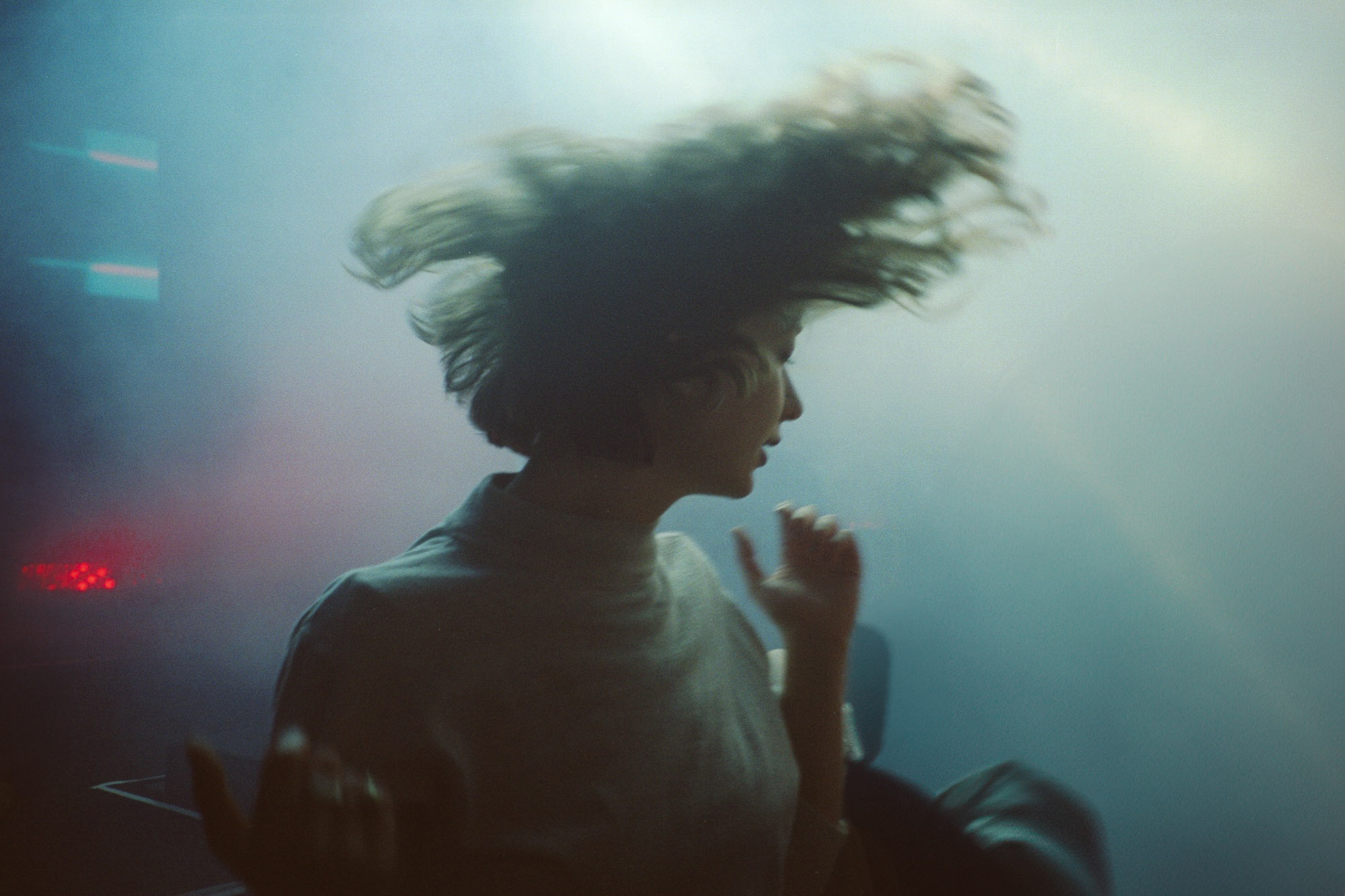 A person with flowing hair is silhouetted against a misty, colorful background, creating a dynamic and ethereal atmosphere.