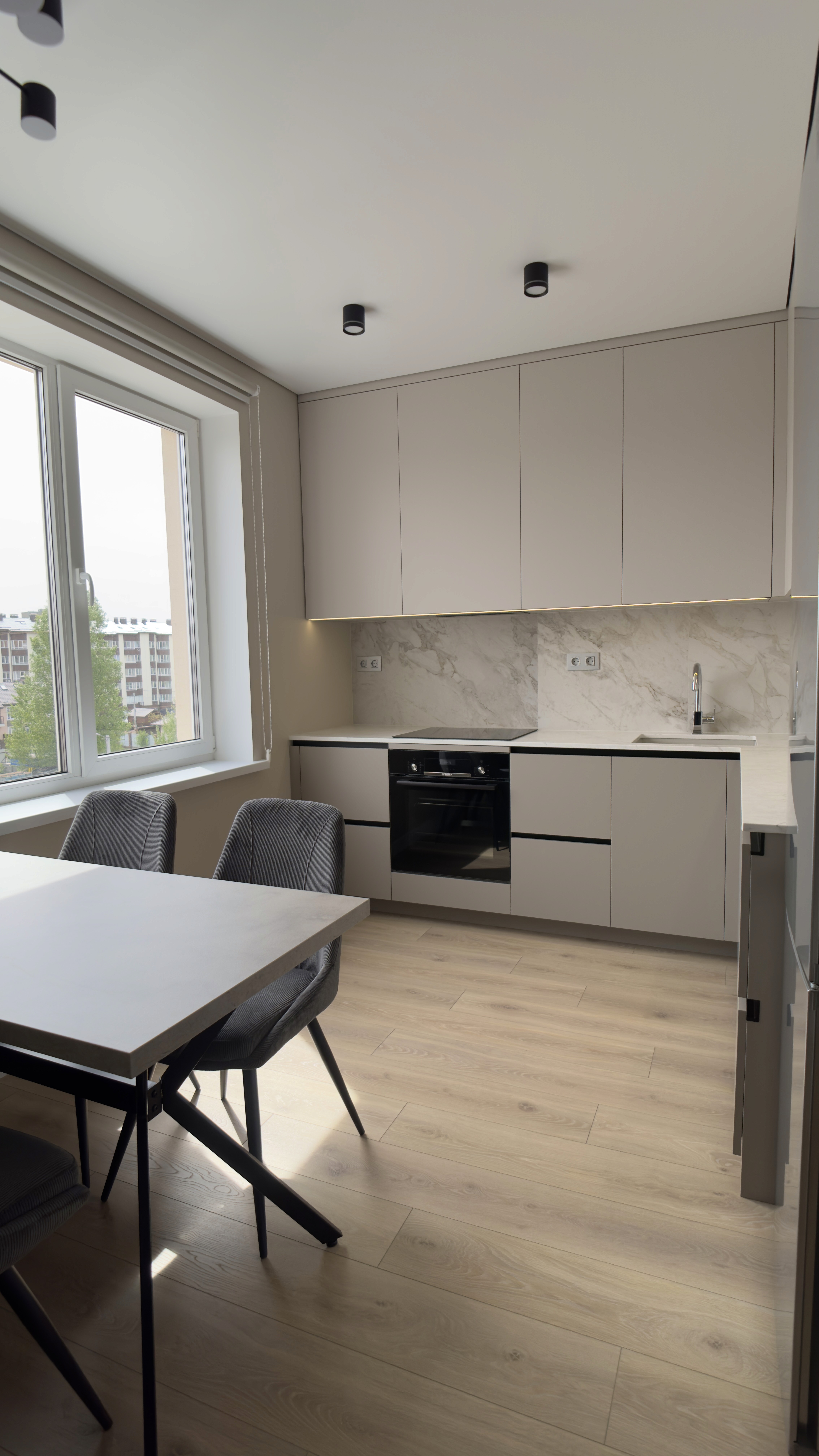 Кухня з вікном, обіднім столом і вбудованою технікою в лаконічному дизайні