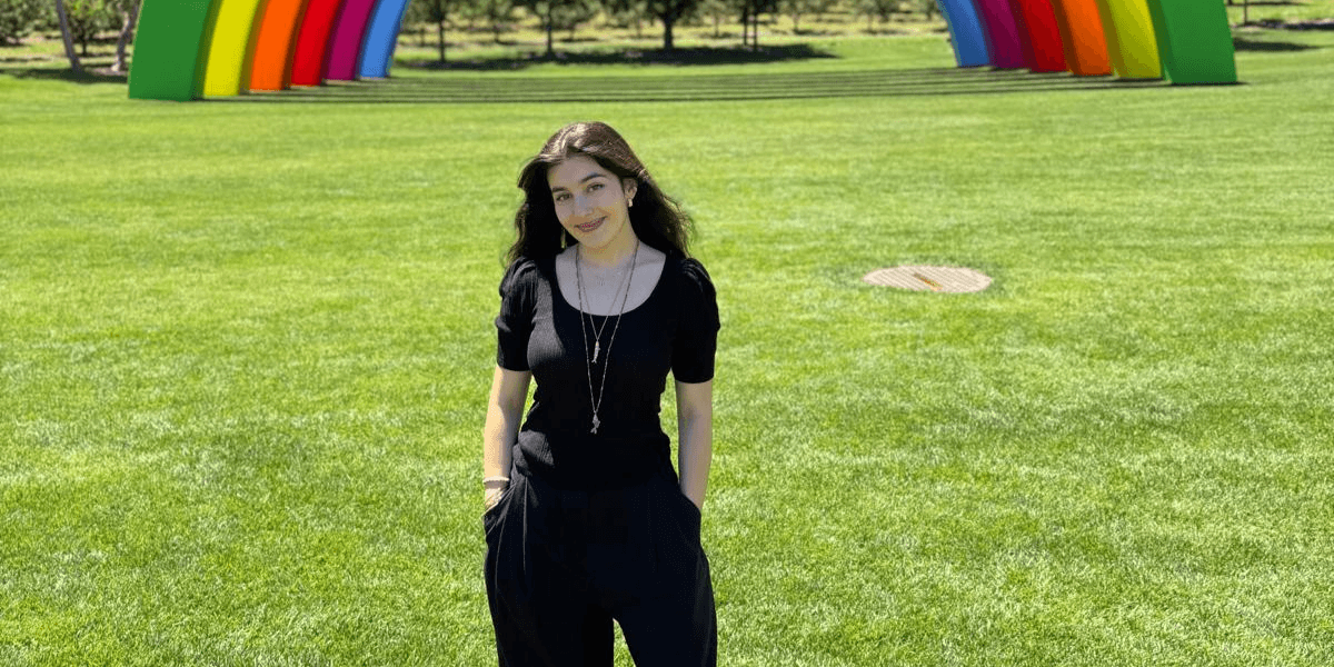 "Anna Belhassen standing in front of a colorful rainbow sculpture, representing her innovative work in neurotechnology and engineering."