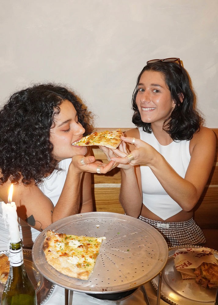 Two girls eating pizza wearing several silver rings