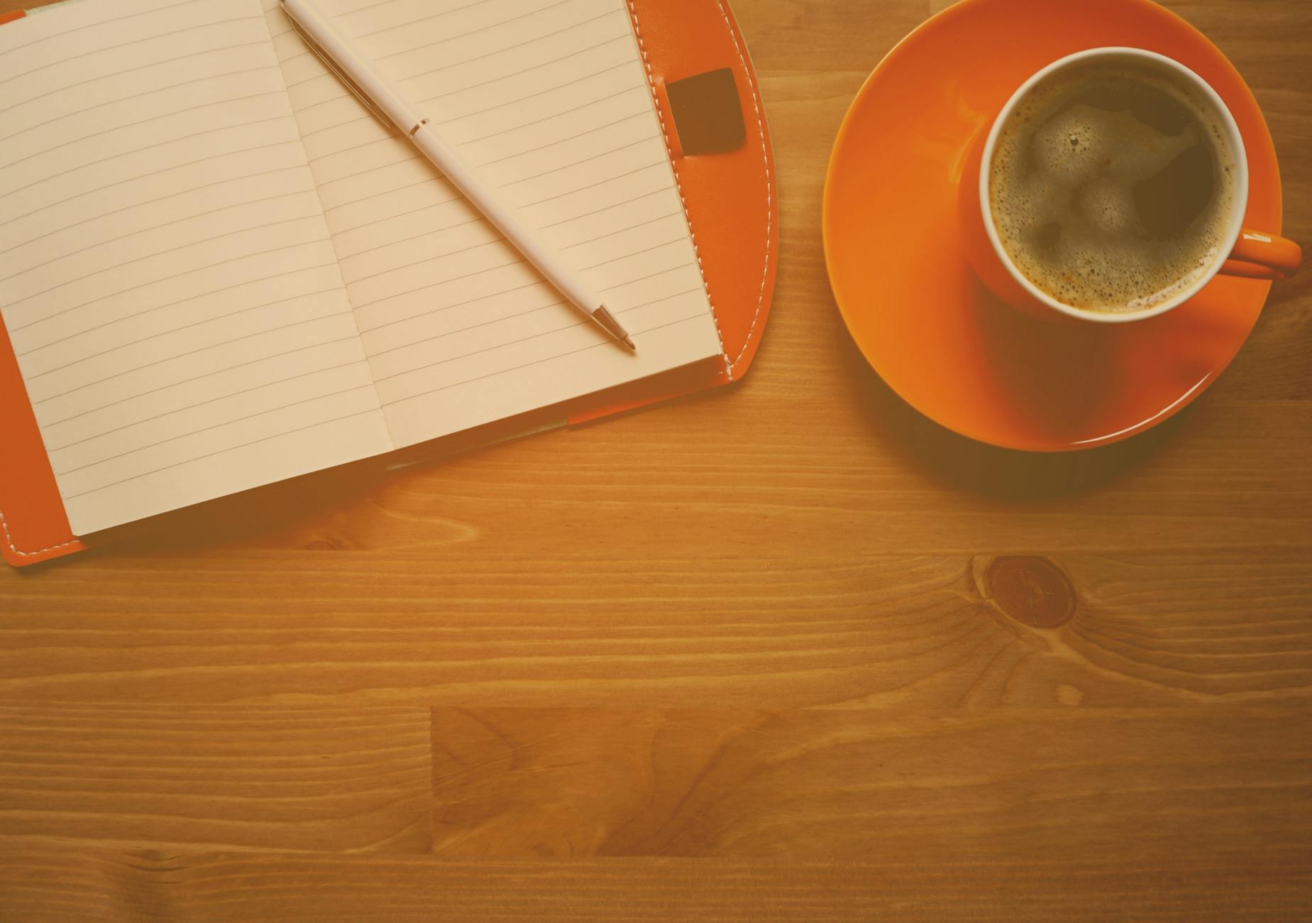 A teacher smiling while holding a steaming mug of tea and looking out a classroom window during a quiet break.