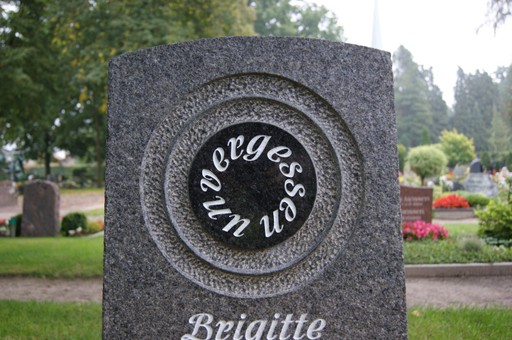 Dunkler Granitstein mit dem Wort „unvergessen“ in einem geschliffenen Ring