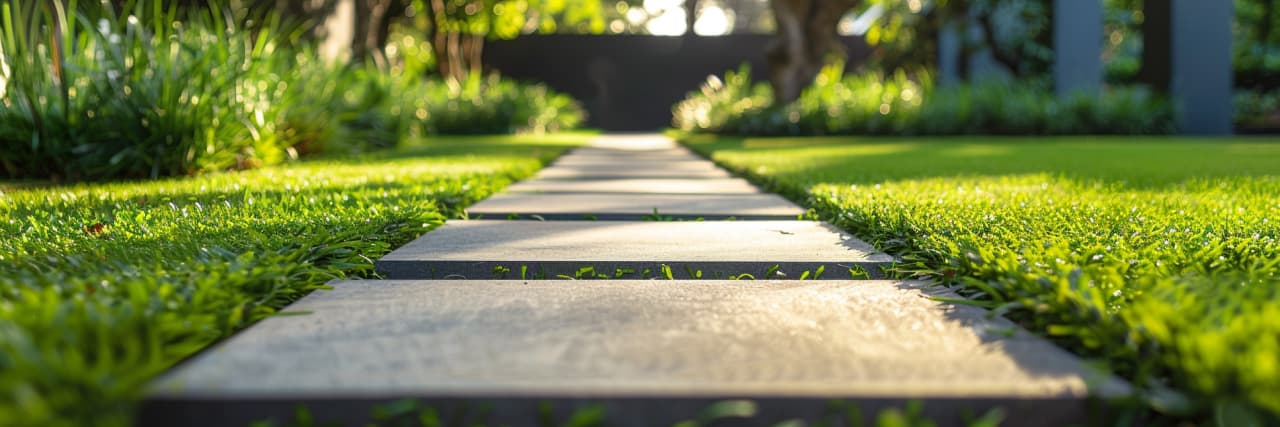 Stepping stone path through fresh green lawn, clean grass installation in modern garden