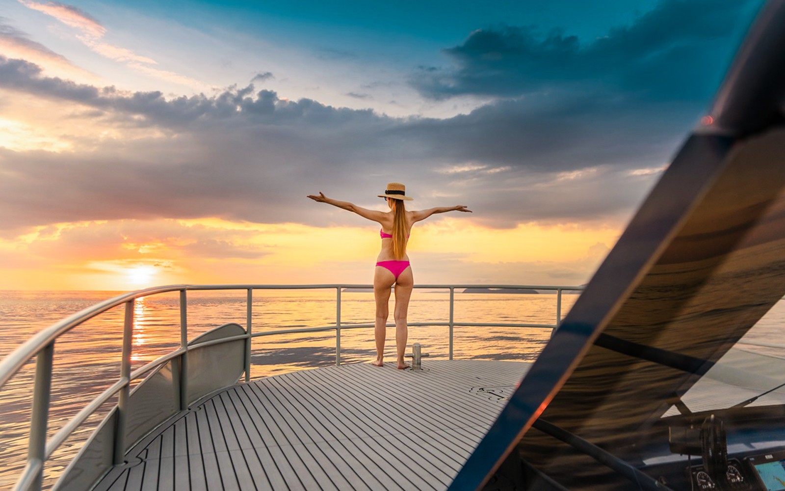 游客在游艇甲板上欣赏海洋日落美景。