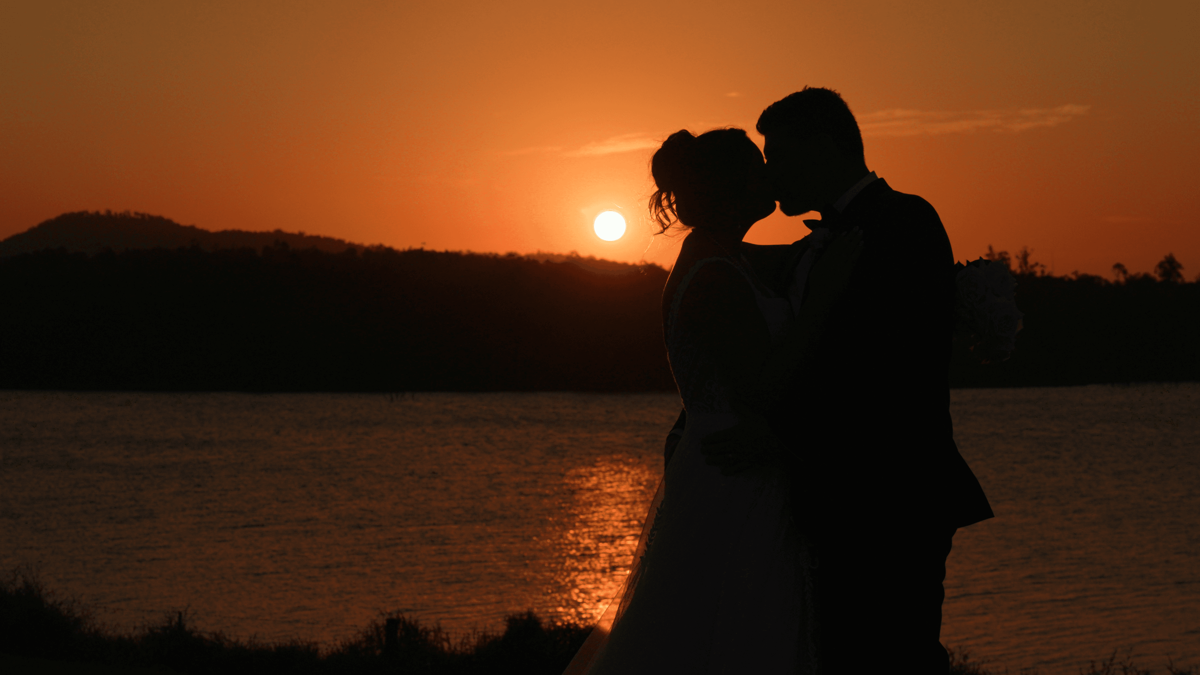 Lauren &. Mike standing in front of an epic sunset at The Overflow Estate in Wyaralong in the Scenic Rim, Queensland for their Wedding Videography from Creo Bella.