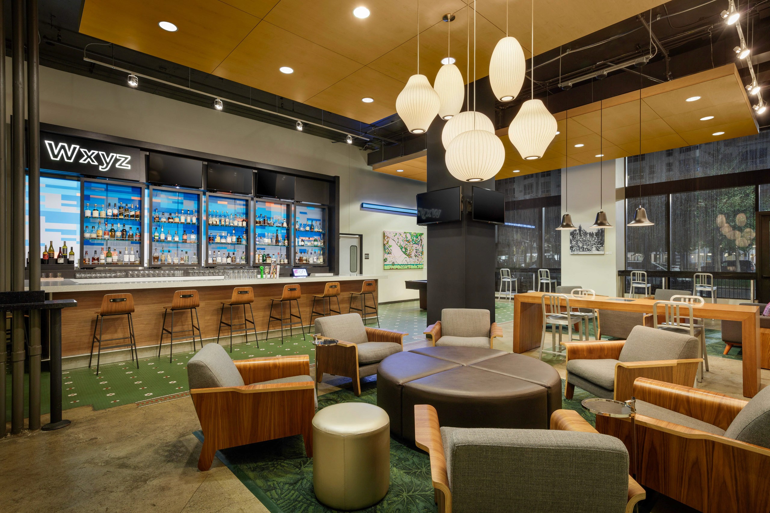 Modern lounge with bar, seating, and pendant lights.