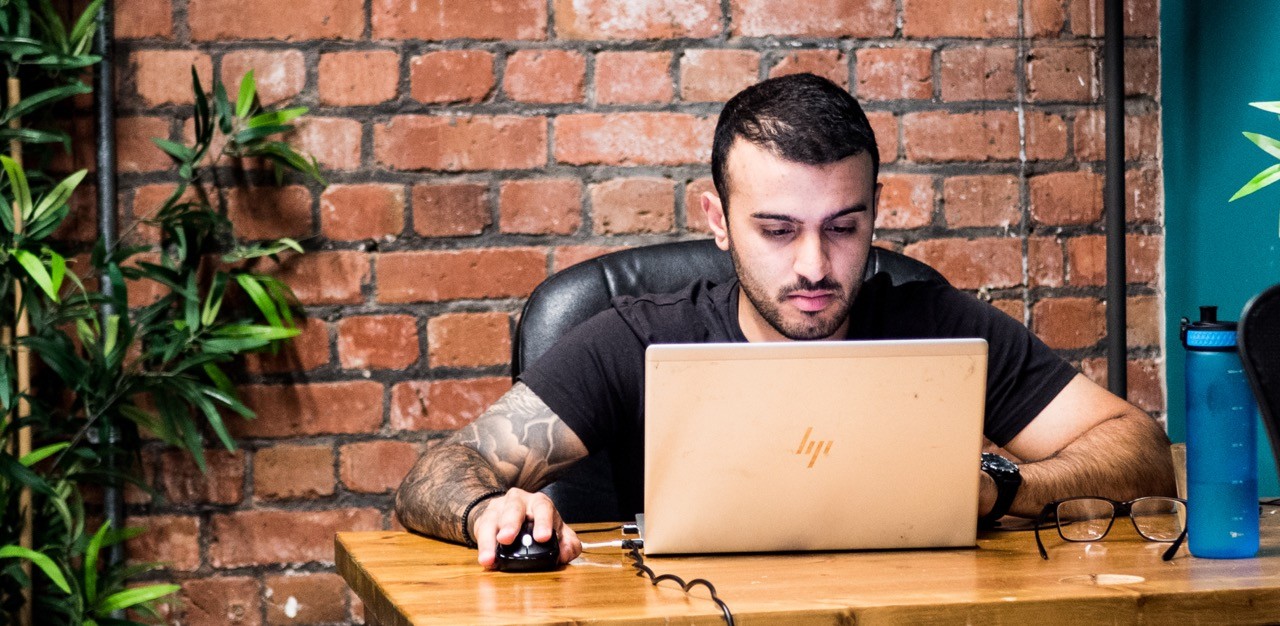 A person using a laptop while sitting at an outdoor table.