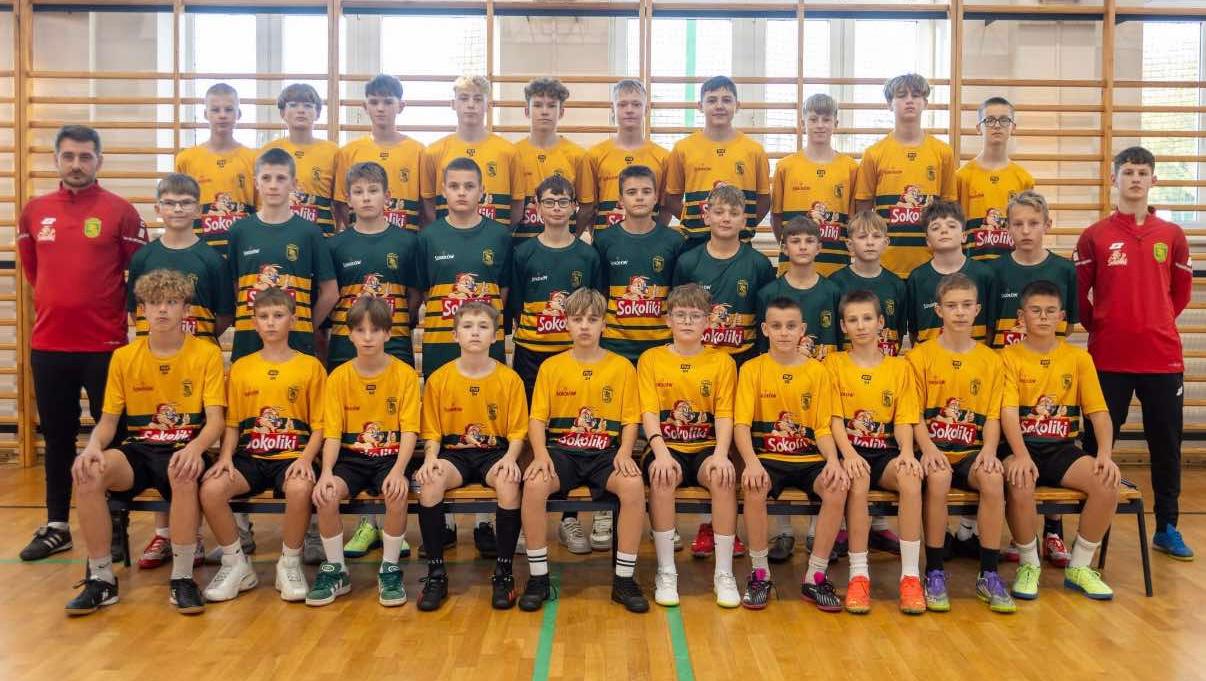 A woman with auburn hair and a gray coat over a white sweater, set against a neutral background, exuding a minimalist aesthetic.