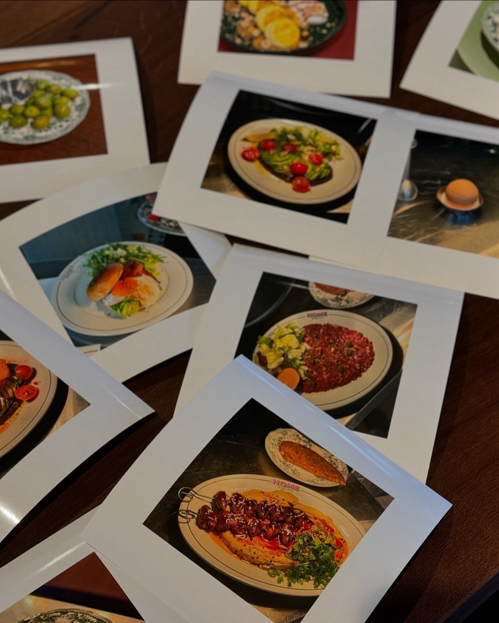 A collection of photographs showcases various dishes, including grilled skewers with vegetables, a burger plated with fresh greens, a salad with cherry tomatoes, and a pasta dish garnished with herbs, all displayed on a wooden surface.