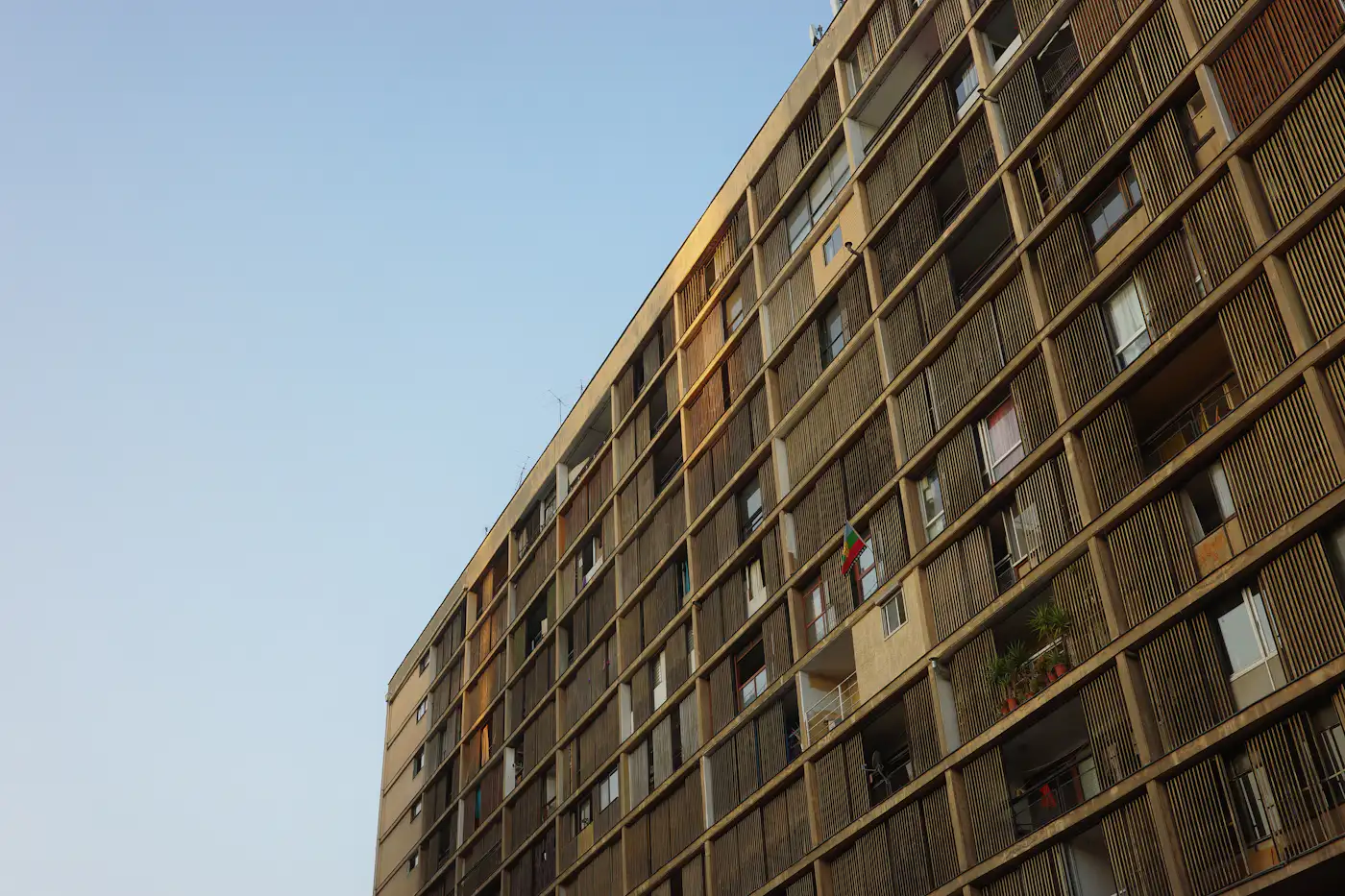 A tall apartment building with many windows against the sky