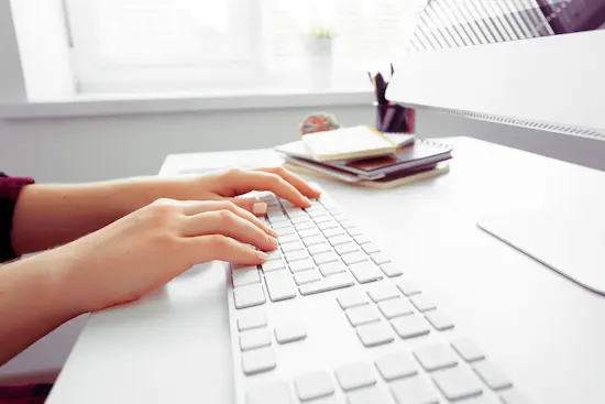 mains de femme créatrice site web devant clavier et écran d'ordinateur