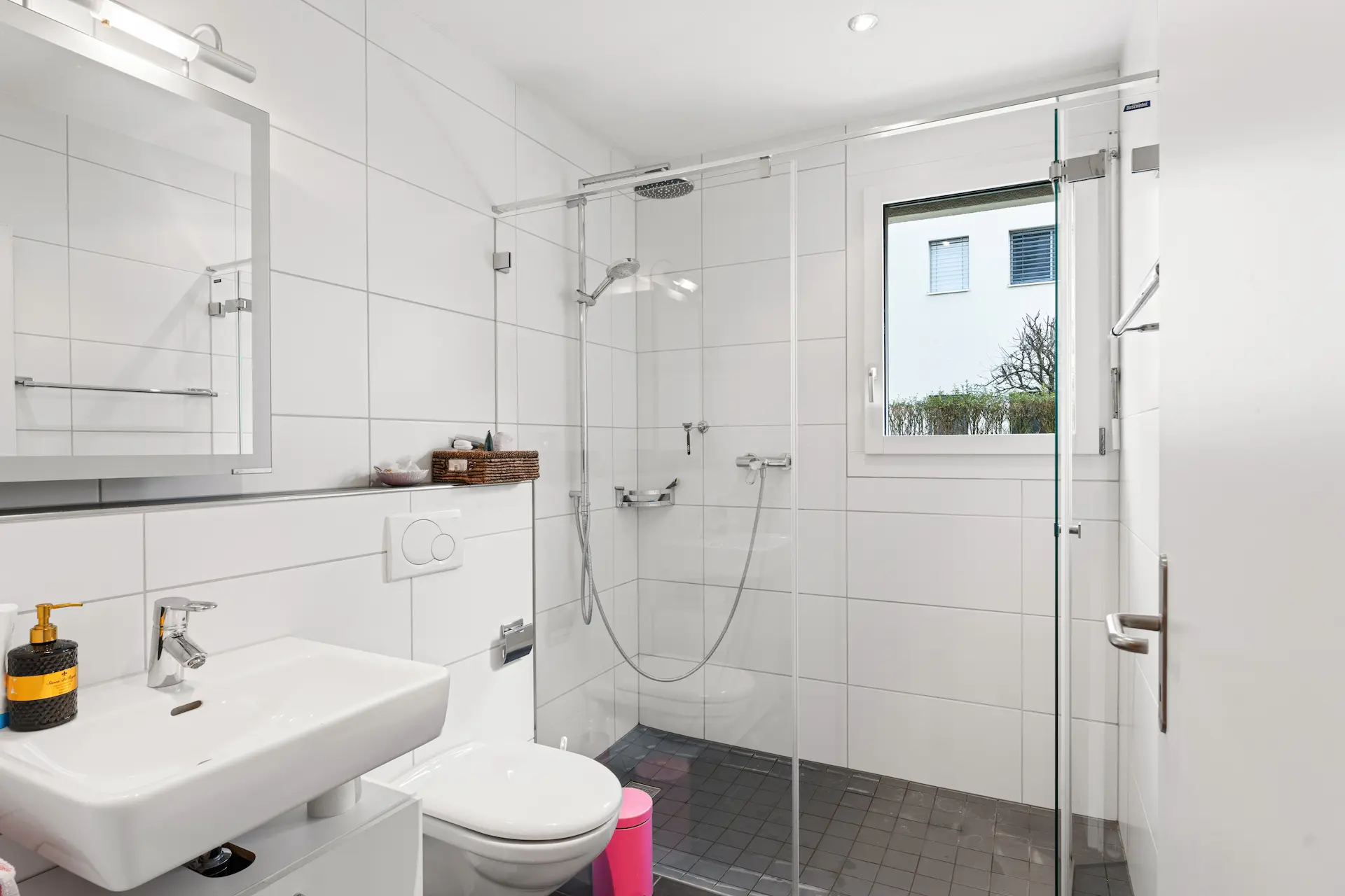 Weisses Badezimmer mit Dusche, Tageslicht und modernem Spiegelschrank