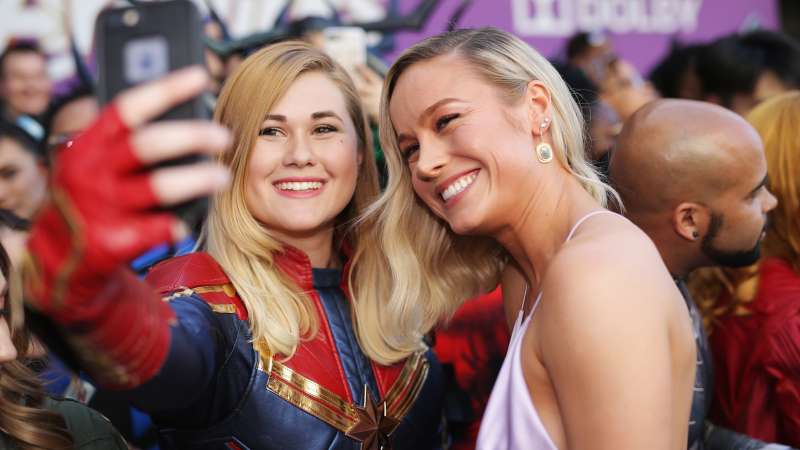 Actress Brie Larson poses for a selfie with a Captain Marvel cosplayer at a movie premiere. 