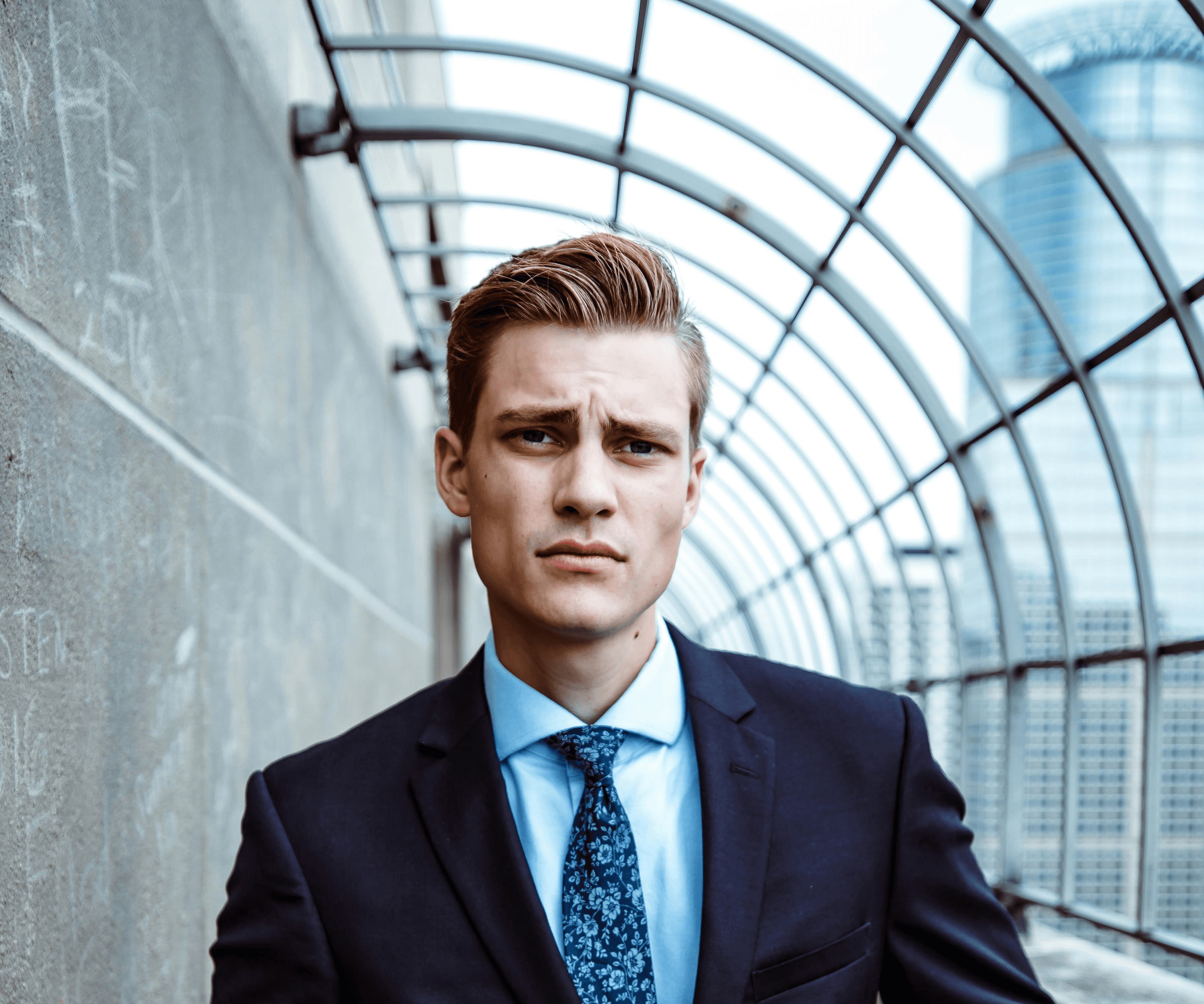 man wearing black and teal dress suit standing near gray wall