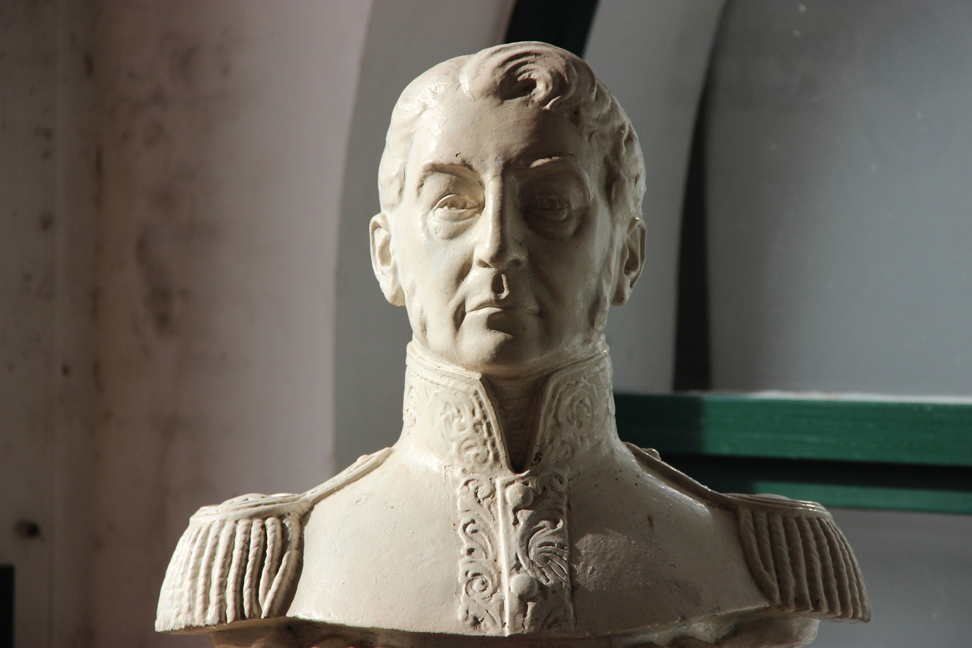 Busto de figura de San Martín con uniforme detallado, exhibido en interior de museo.