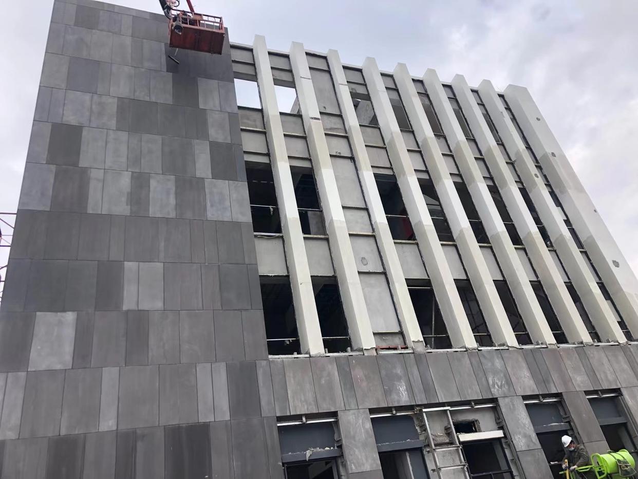 A modern building with exterior stone cladding, featuring a light beige travertine finish, commonly used in luxury and minimalist designs.