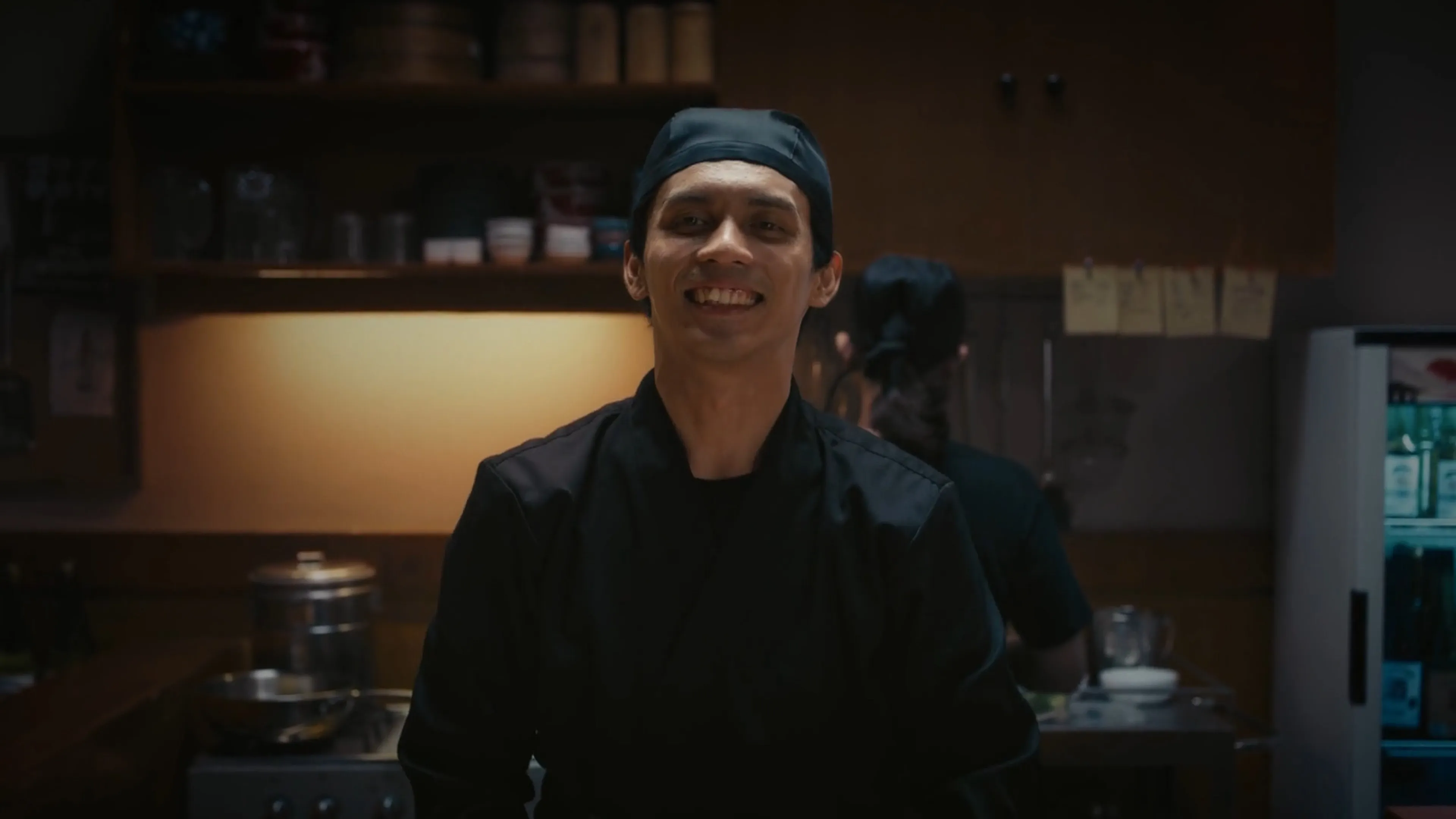 Indonesian chef smiling to customer in Tokyo kitchen setting in cinematic brand film for DCOM Money Express, produced by Visual Producer Indonesia