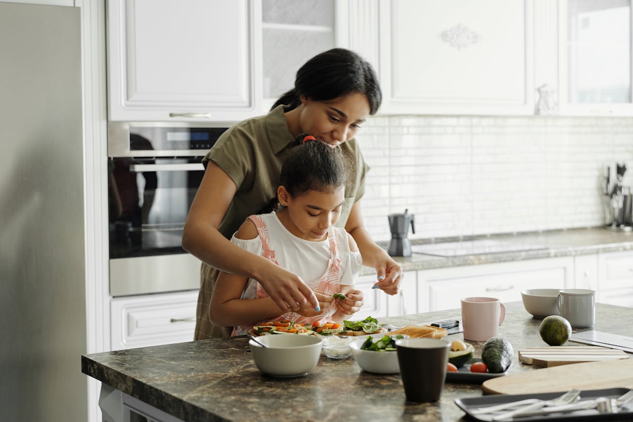 A mother and daughter prepare avocado toast for breakfast.