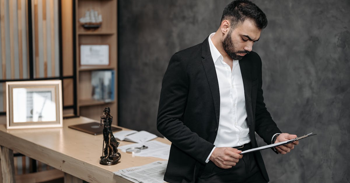 A male lawyer in a black suit focusing on paperwork in an office setting.