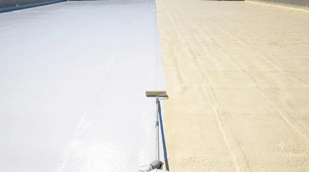 White silicone topcoat being applied over cured spray polyurethane foam on a Florida commercial roof