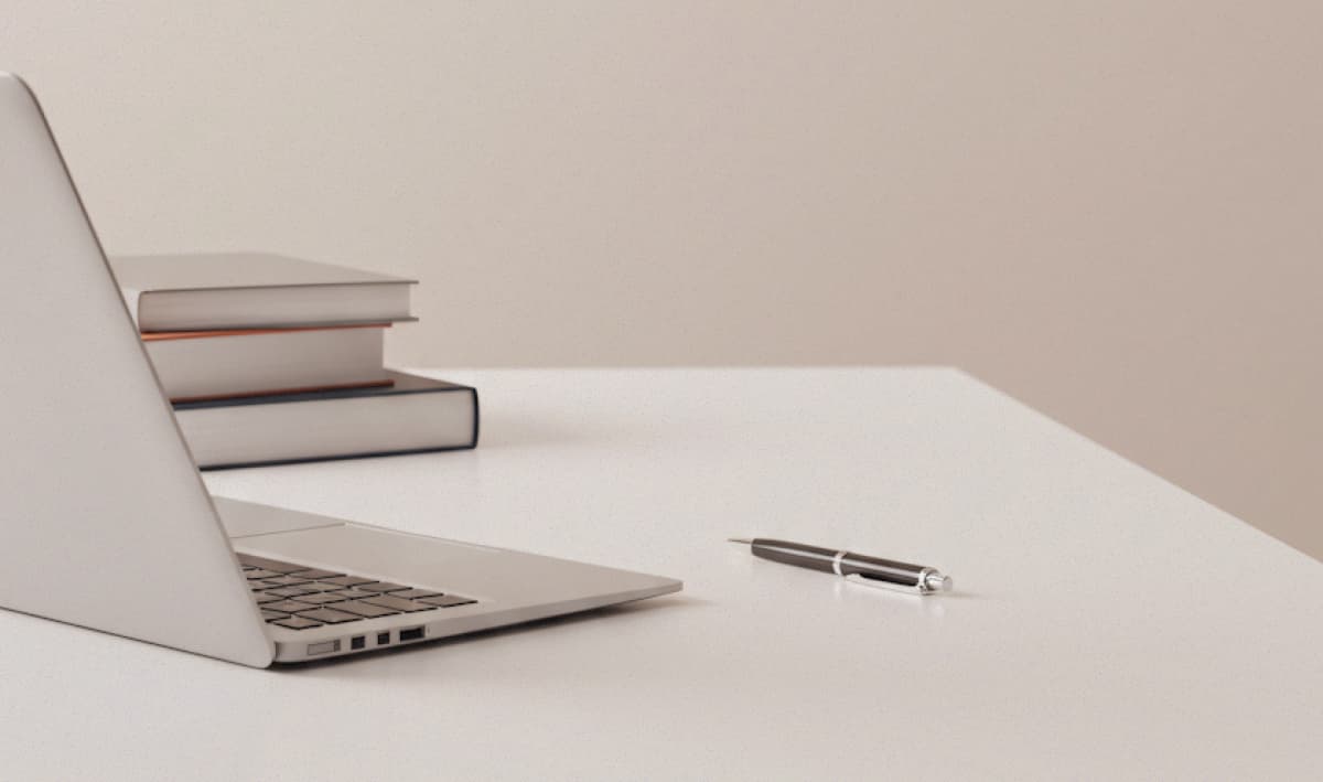 Minimalist beige workspace with laptop pen and books 