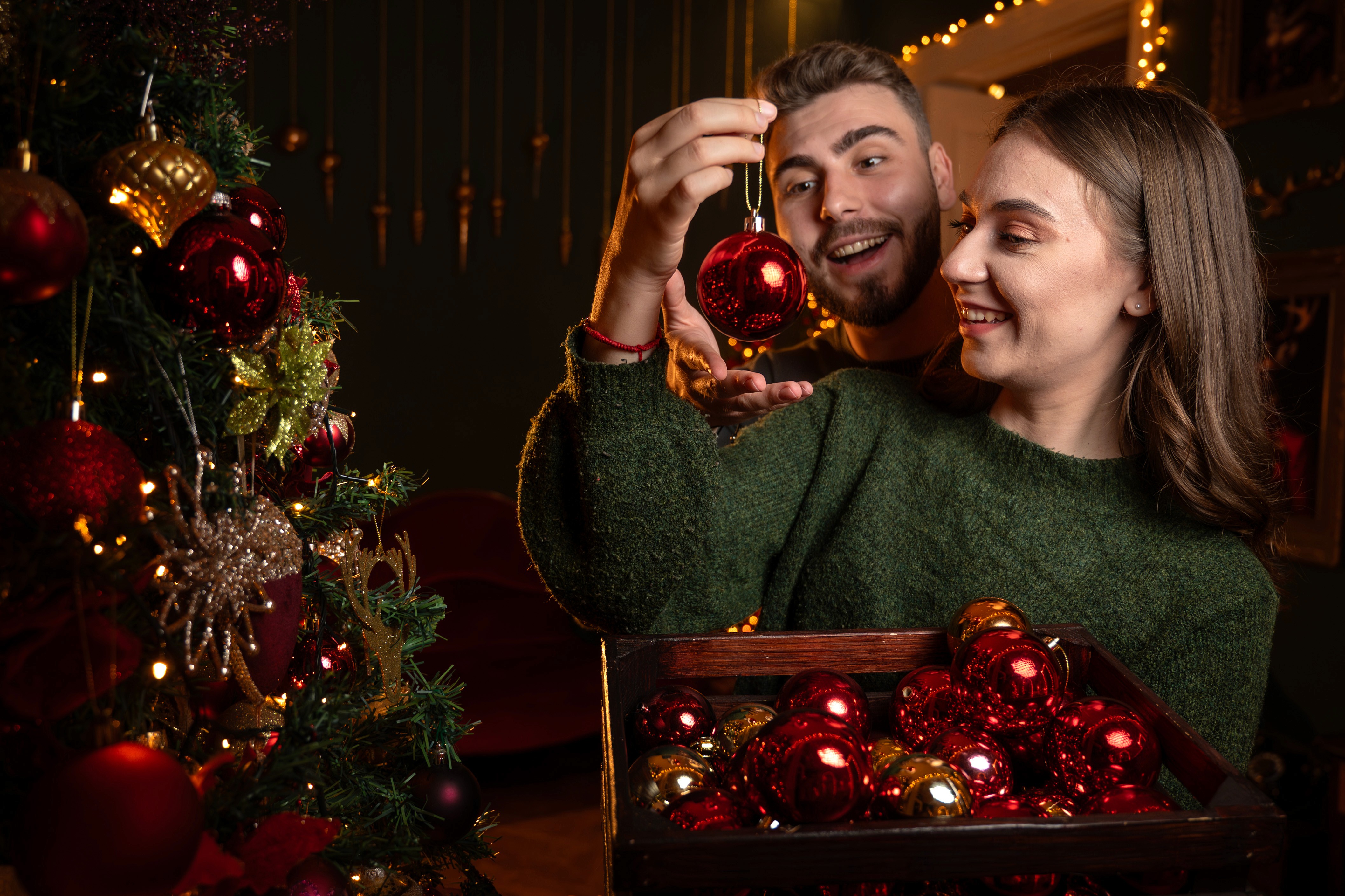 Ședință foto de Crăciun cu cuplu într-un decor festiv cu brazi împodobiți și lumină caldă, fotografie de sărbători București.
