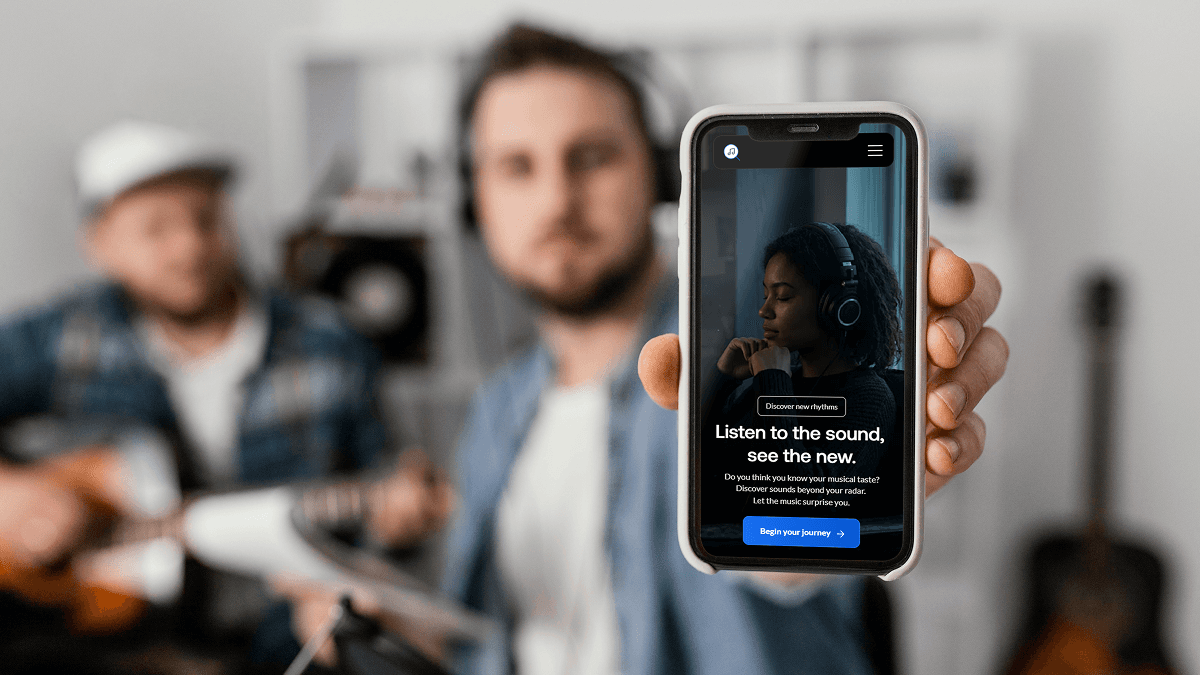 Portrait of a woman with curly hair wearing a two-tone gray and orange beanie against a neutral background.