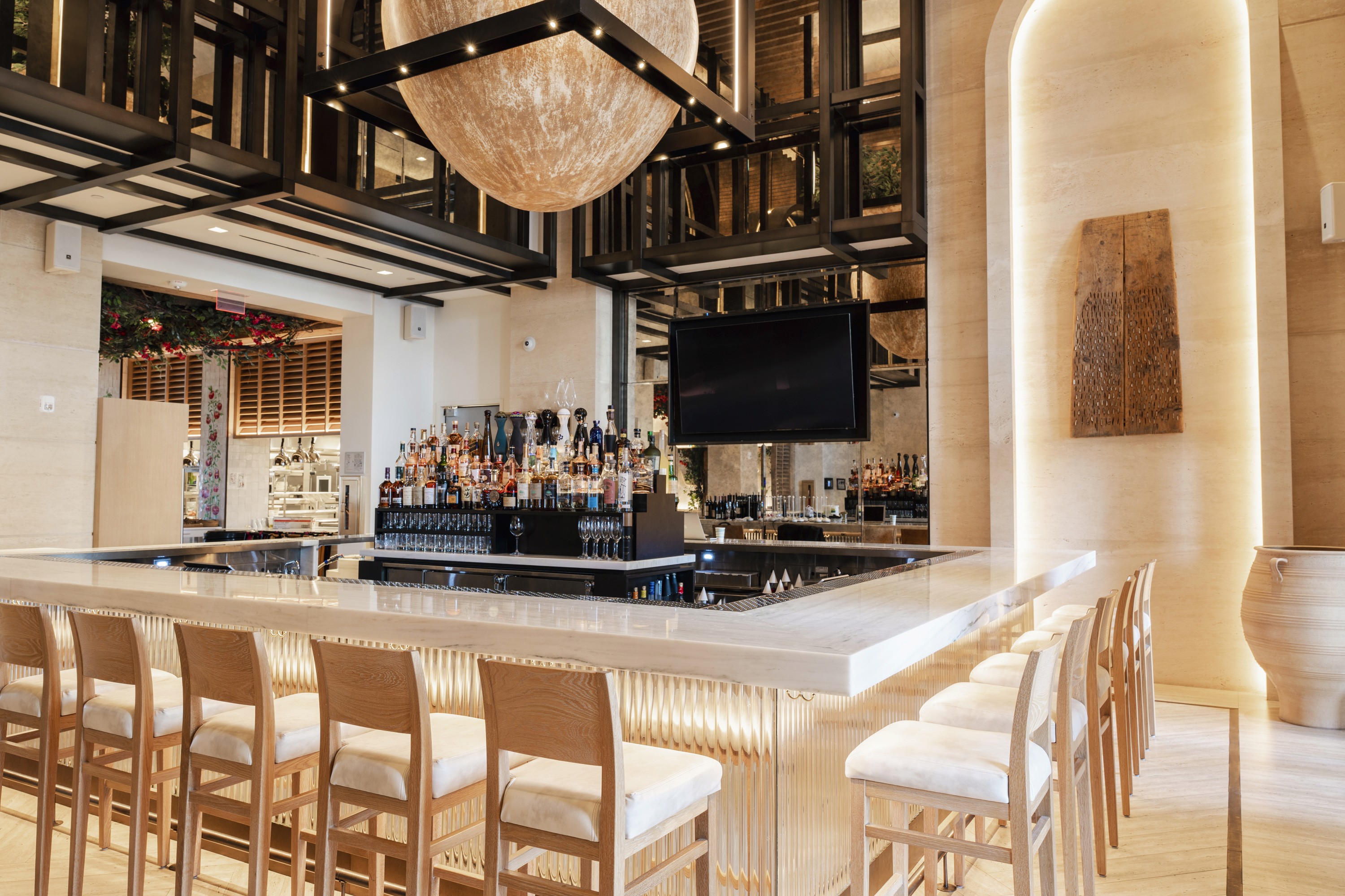 Modern bar interior with wooden stools, a sleek counter, and elegant lighting fixtures creating a warm atmosphere.