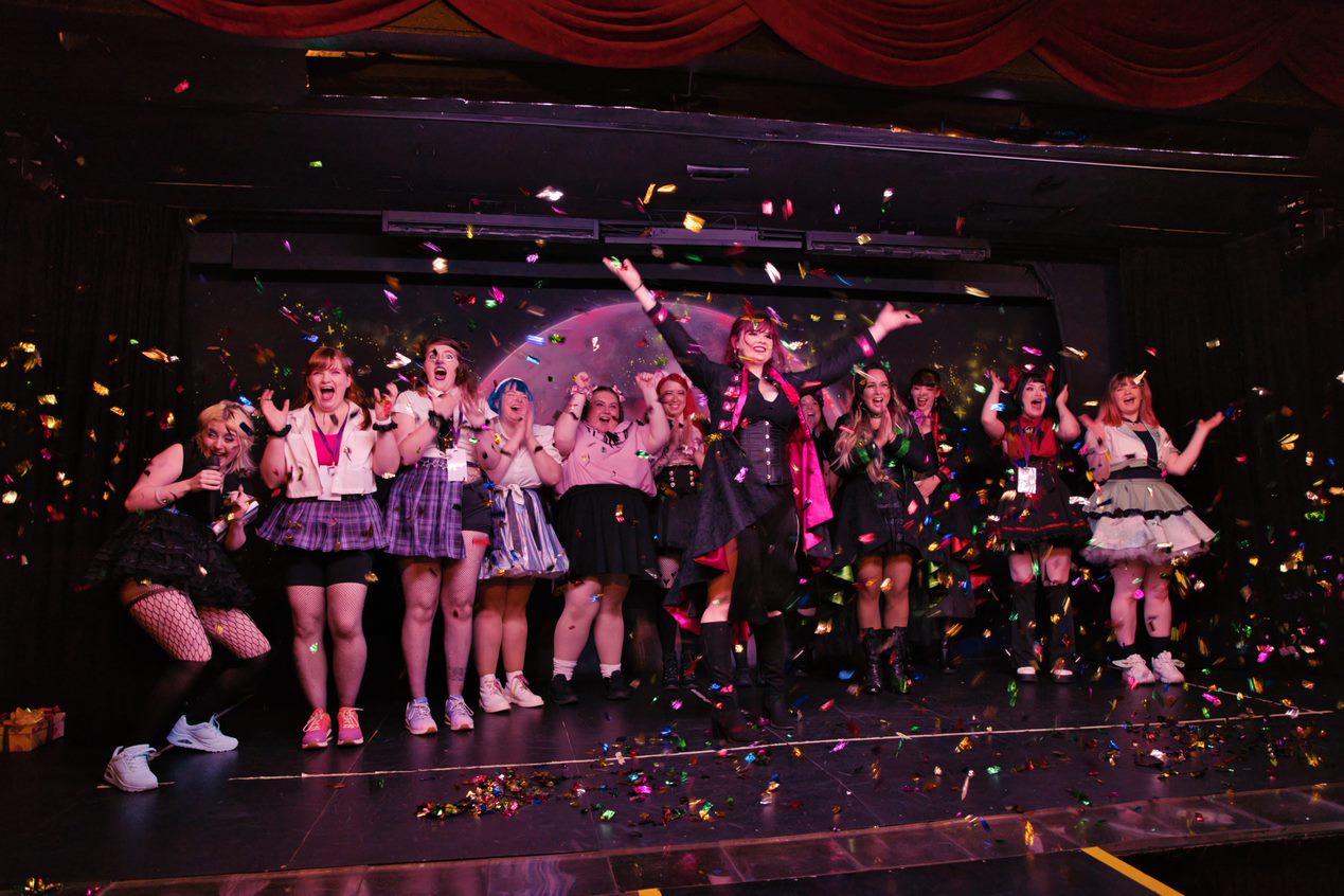 stage full of cosplayers at the announcement of a winner, confetti streams from the ceiling