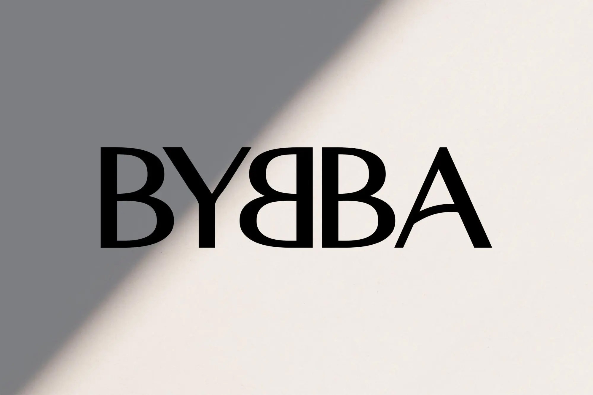 A black and white photo of a person with curly hair sitting on a chair in a barren, textured landscape.