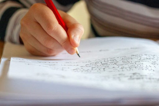 person writing on white paper illustrating the French Level Needed for Citizenship in France