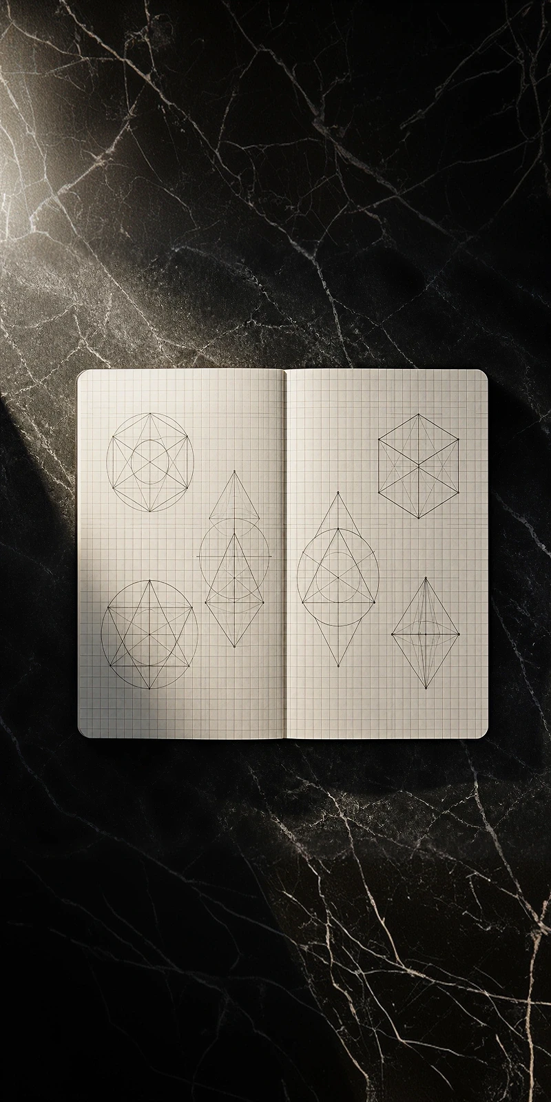 Geometric wireframe sketches on grid notebook over black marble — representing systematic design thinking and structural precision