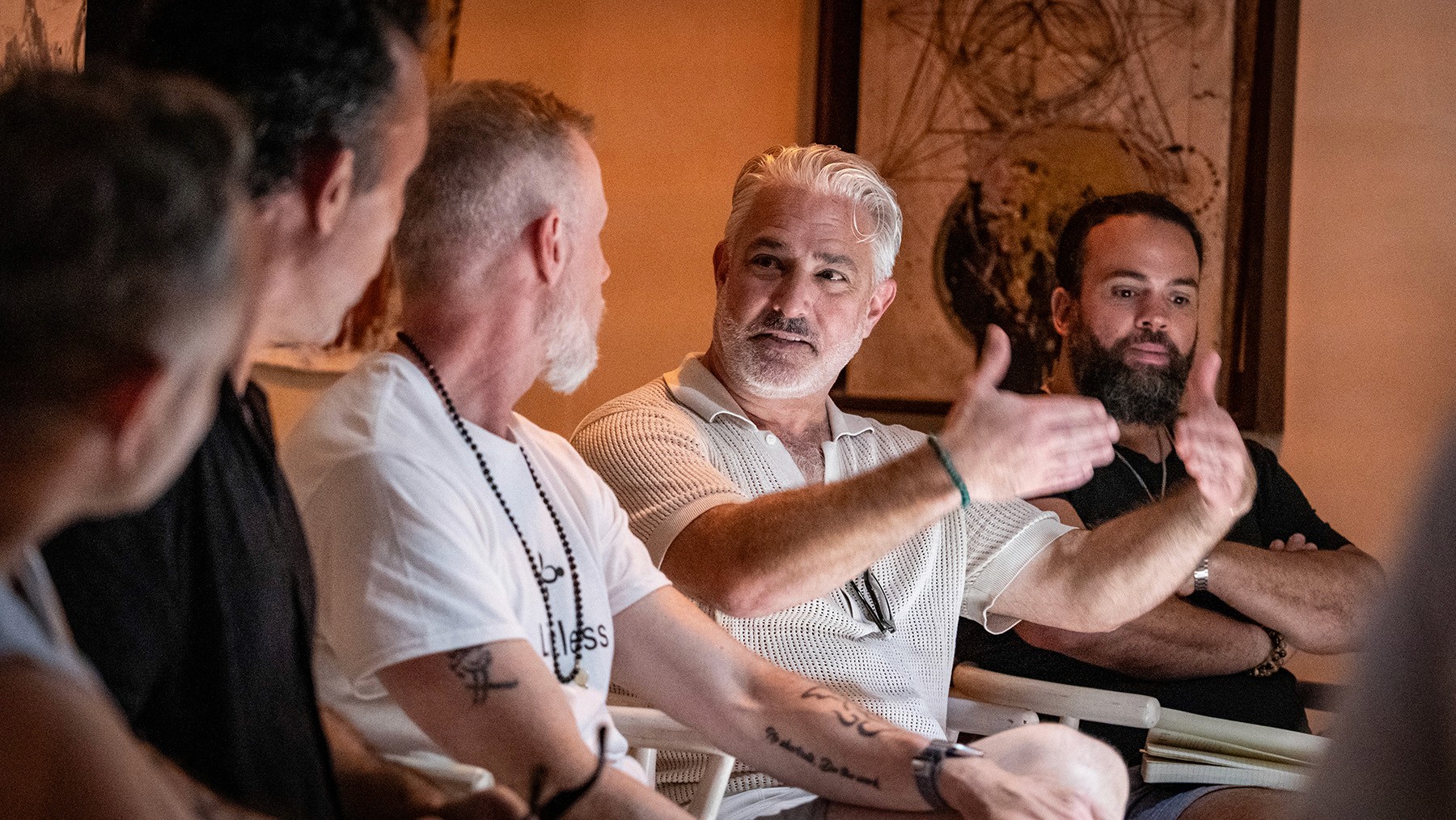 Men in a meeting, one man gestures with his hands while speaking.
