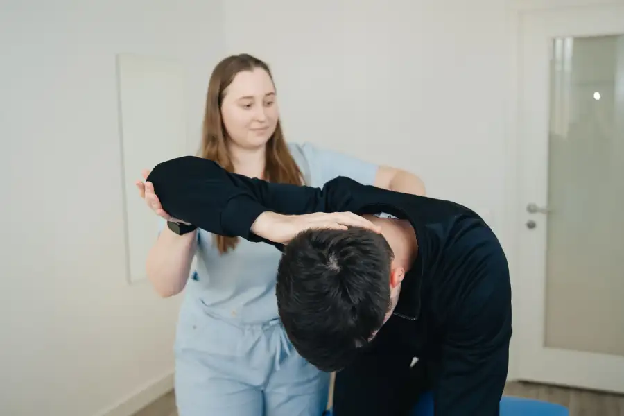 chiropractor performing manual muscle testing on patient's shoulder