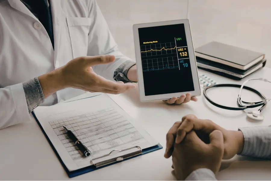 AI medical consultant showing a patient real-time heart rate monitoring data on a tablet during a clinical consultation.
