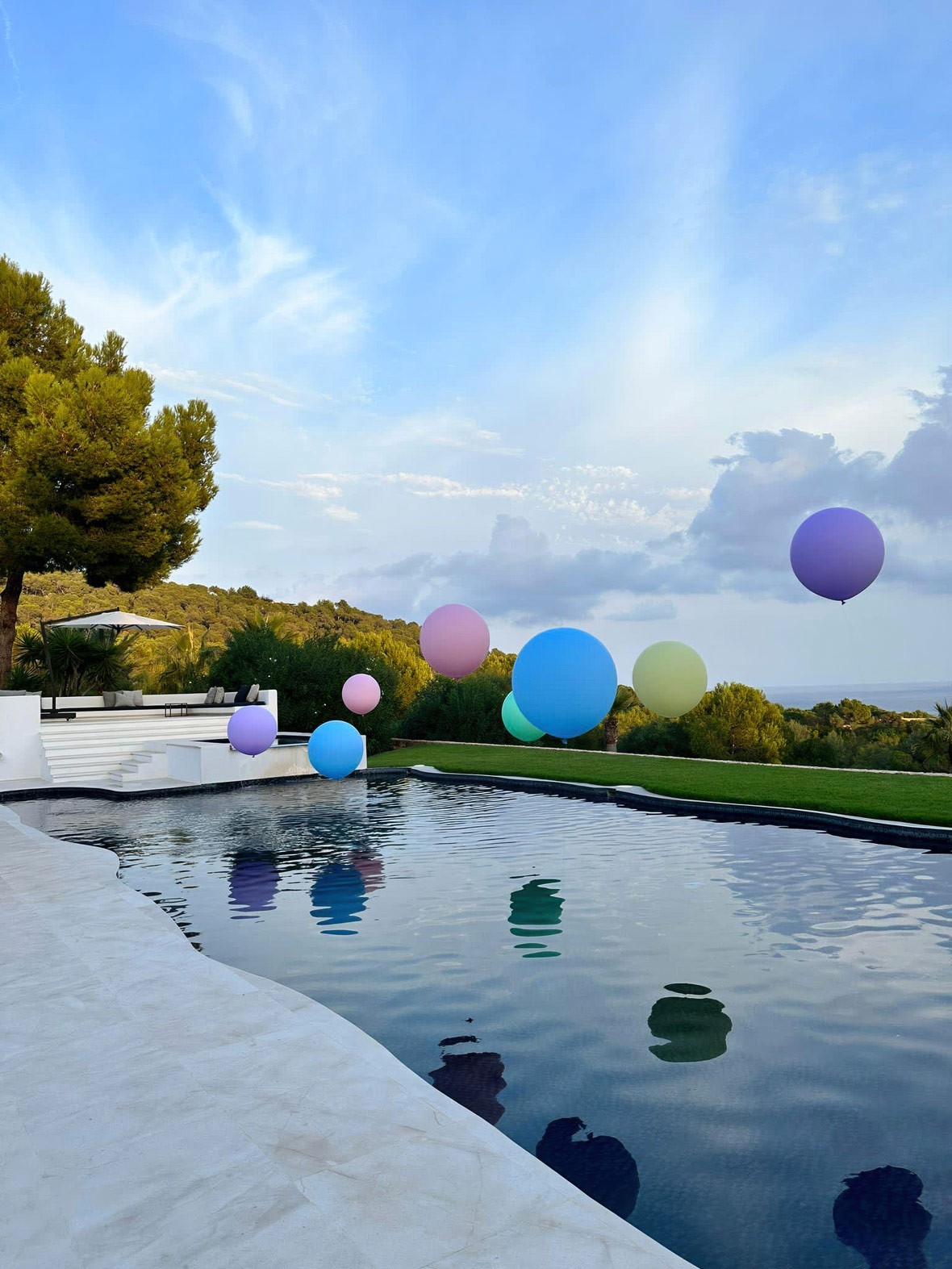 Private event lawn and pool terrace prepared for luxury celebration with decorative balloons and sunset views.