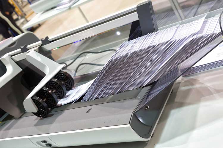 Stacks of envelopes being released from a machine.