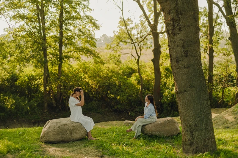 Two woman in forest sitting on stone and talking to each other