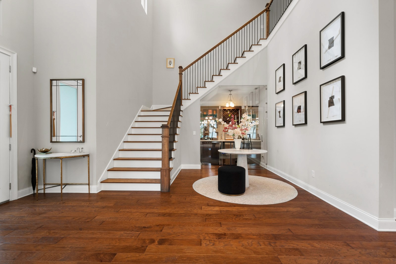 Two-story foyer with wood staircase, dark hardwood floors and a round entry table in a Beach Park home in South Tampa