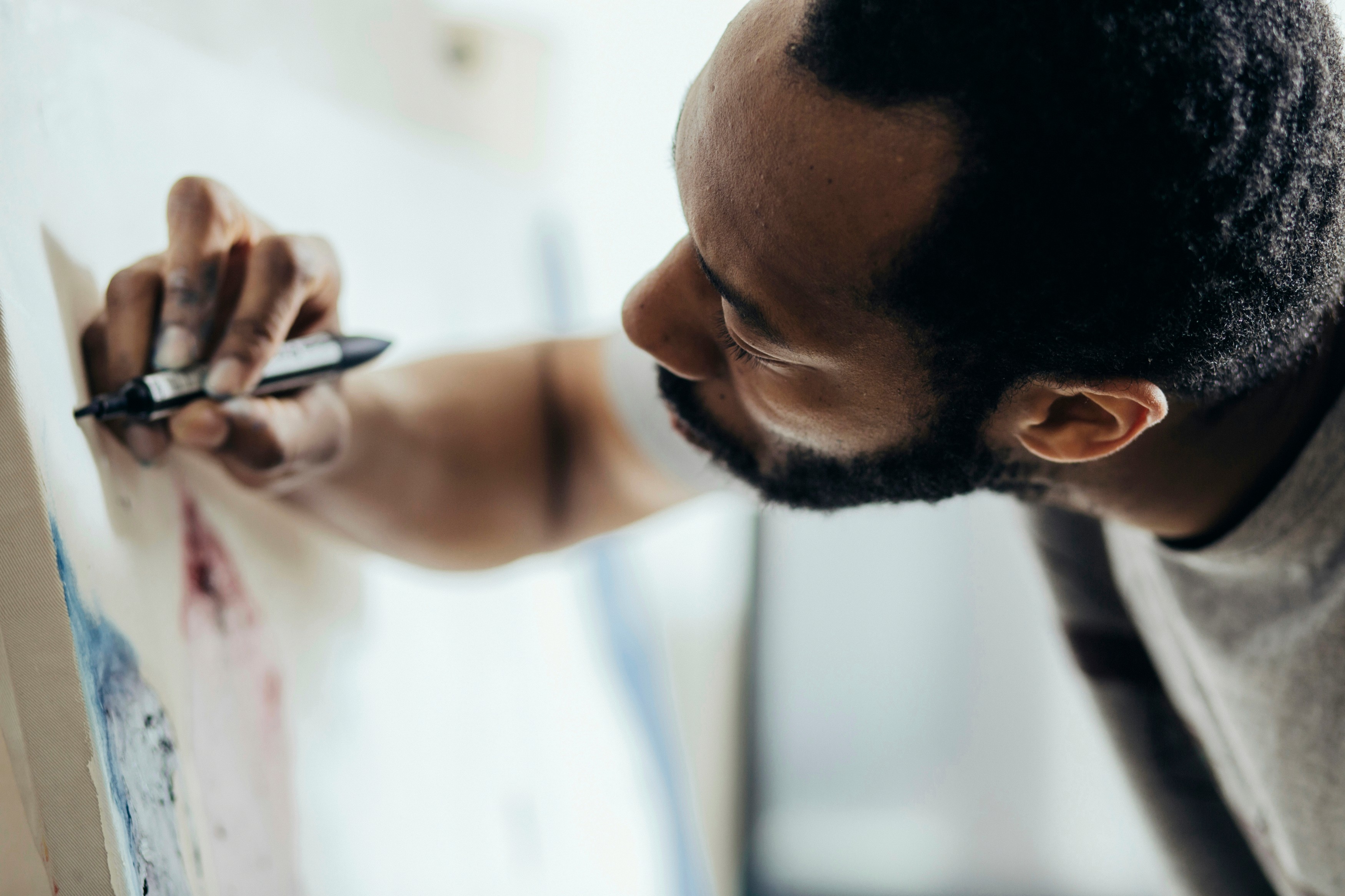 Person arbeitet konzentriert mit der Hand an einer Leinwand – visuelle Metapher für gestalterische Entscheidung, handwerkliche Kontrolle und menschliche Kreativität.