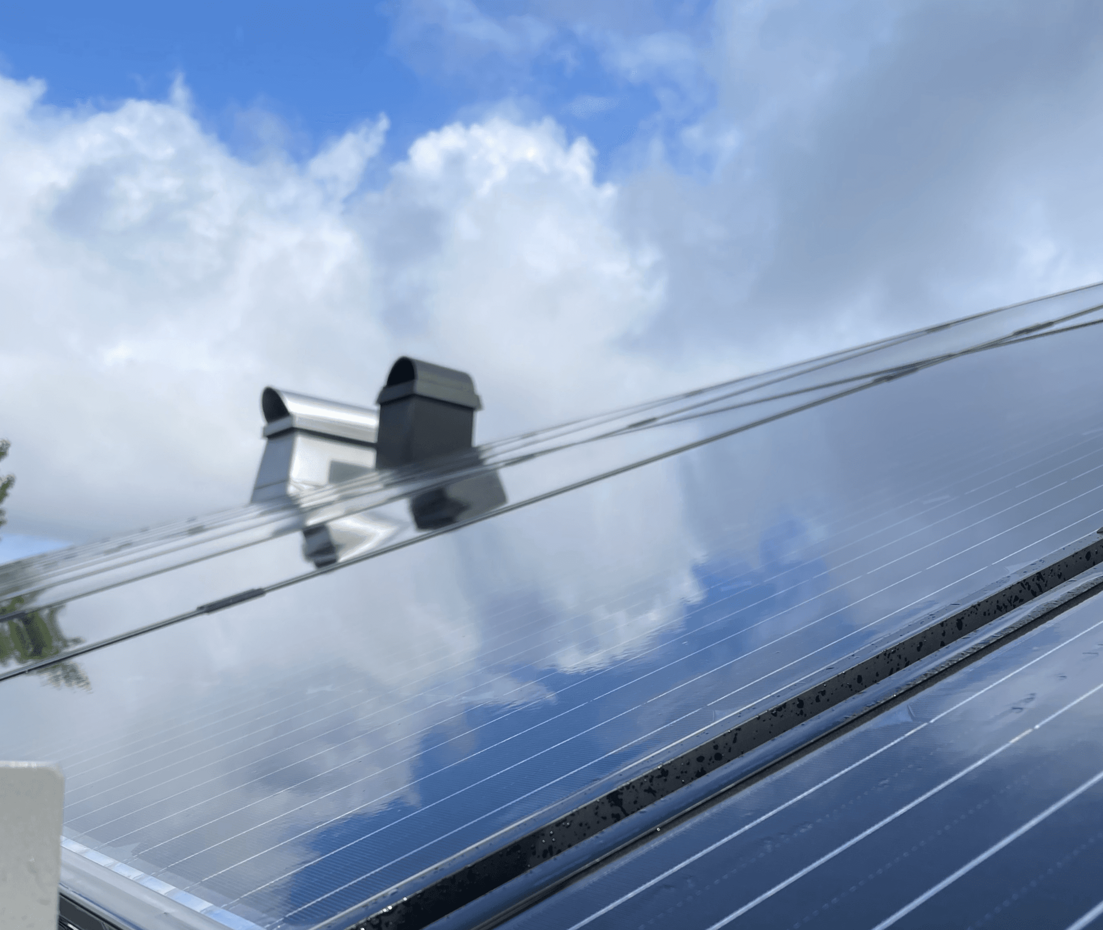 Bild på ett hustak med blänkande solceller och två skorstenar