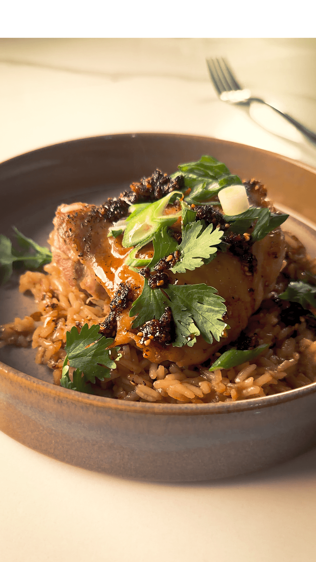 chicken and rice on a grey plate drizzled with chili crunch oil and cilantro