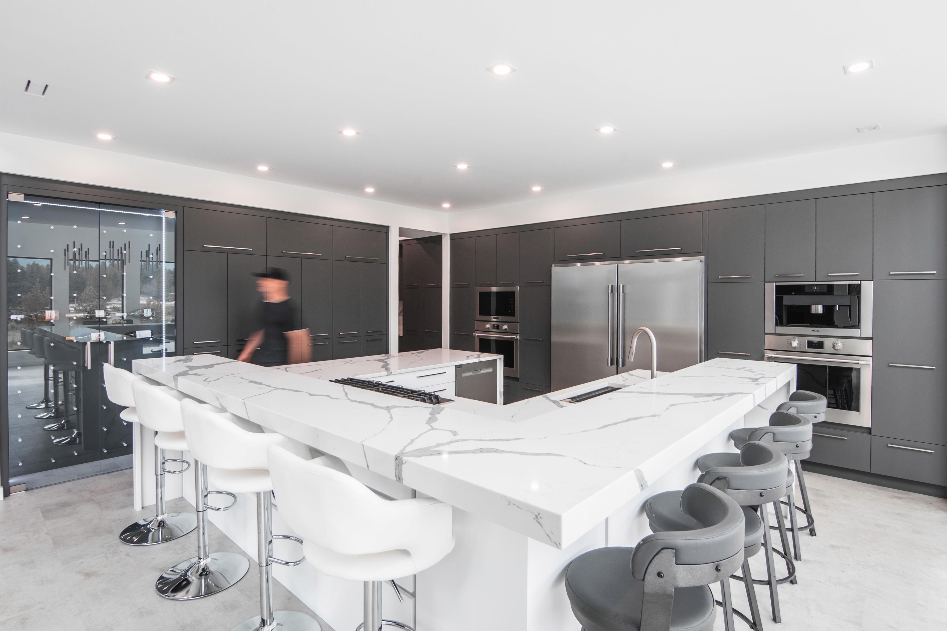 Luxury kitchen with matte grey cabinetry, dual fridges, built-in ovens, and a large white marble island, crafted by J&R Custom Woodwork.